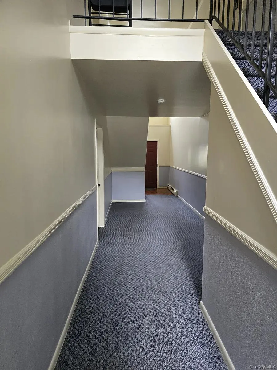 Hall with dark colored carpet and baseboard heating Hall with dark colored carpet and baseboard heating