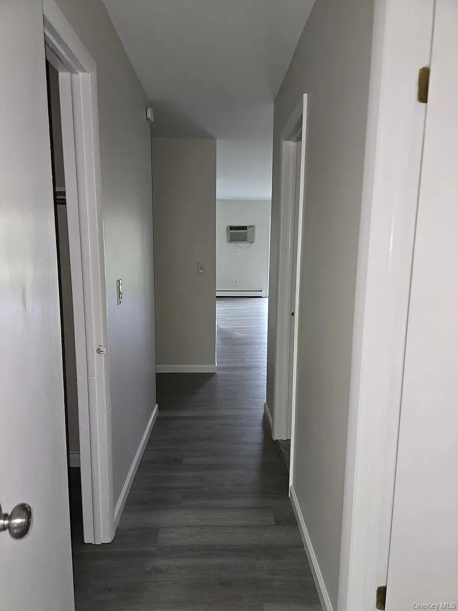 Hallway with baseboards and dark wood-style floors Hallway with baseboards and dark wood-style floors