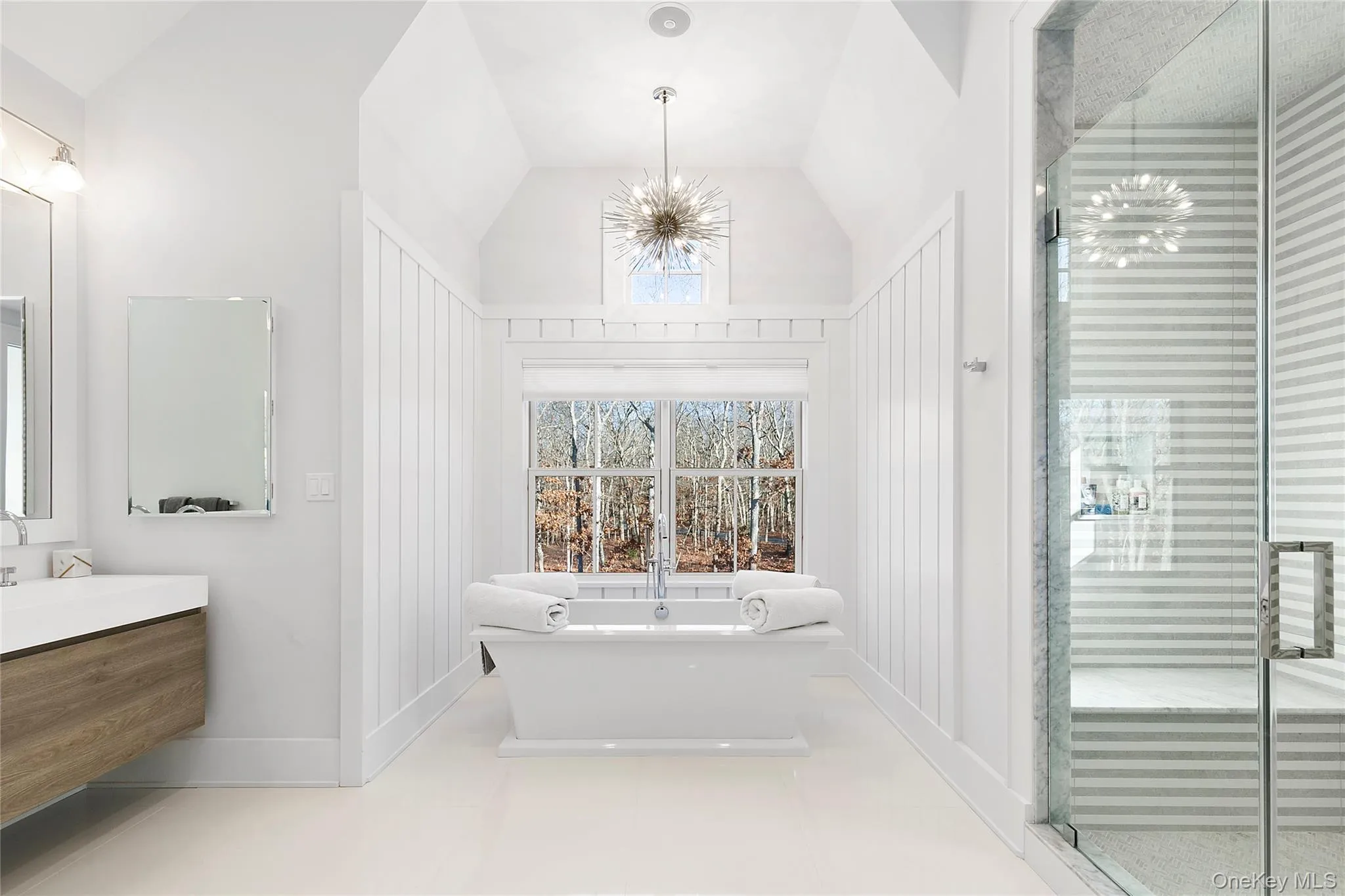 Bathroom with a chandelier, vaulted ceiling, a freestanding tub, vanity, and a stall shower Bathroom with a chandelier, vaulted ceiling, a freestanding tub, vanity, and a stall shower