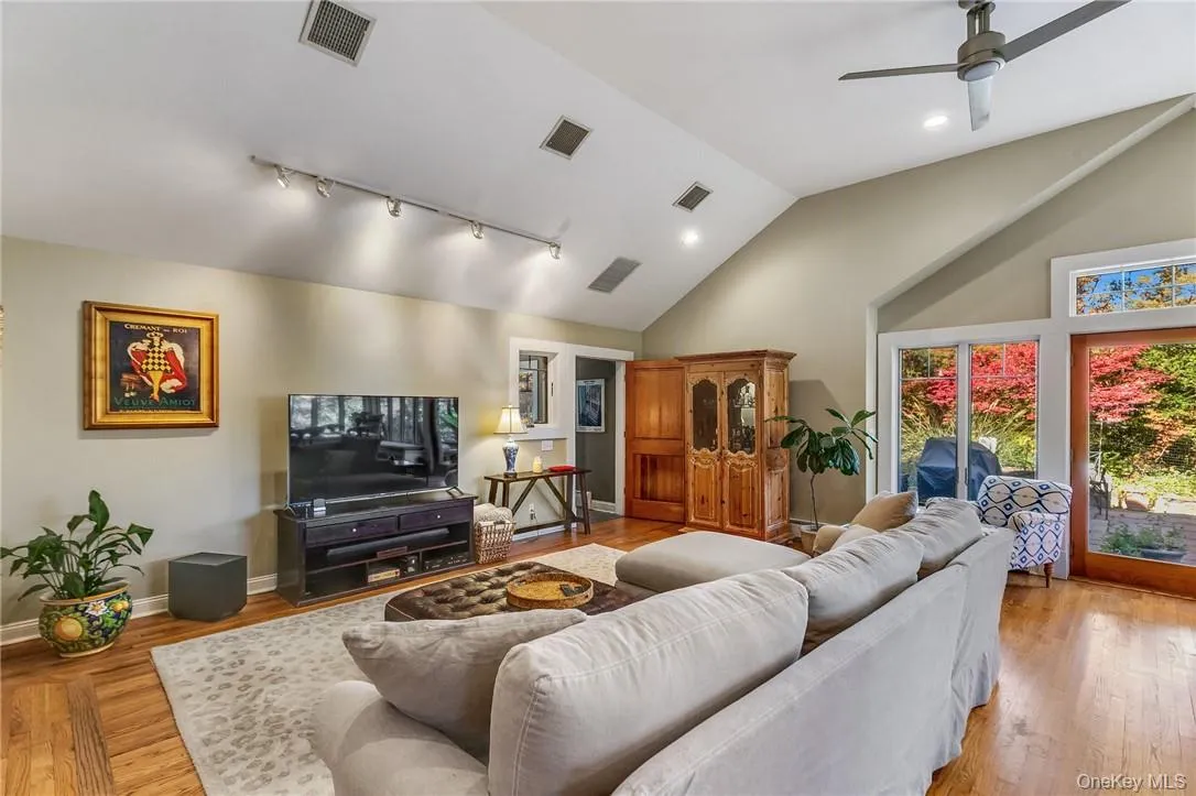 Great room featuring lofted ceiling, hardwood wood flooring, lighting, and ceiling fan Great room featuring lofted ceiling, hardwood wood flooring, lighting, and ceiling fan