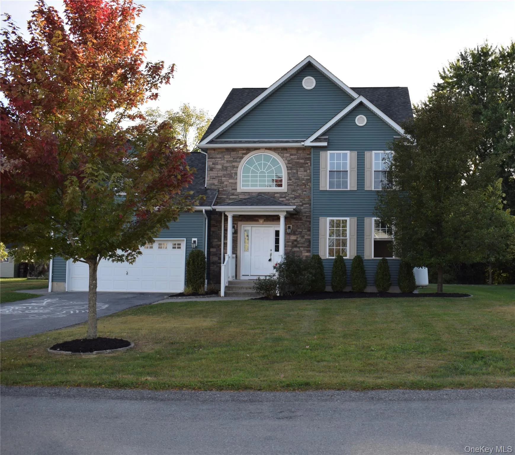 View of front of home with driveway, a front lawn, and stone siding View of front of home with driveway, a front lawn, and stone siding