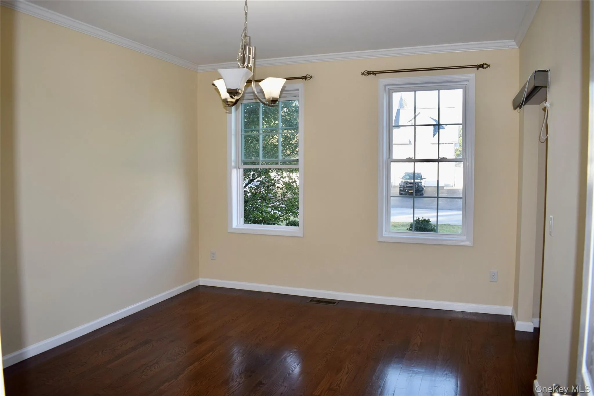 Unfurnished dining area featuring ornamental molding, dark wood-type flooring, and a chandelier Unfurnished dining area featuring ornamental molding, dark wood-type flooring, and a chandelier