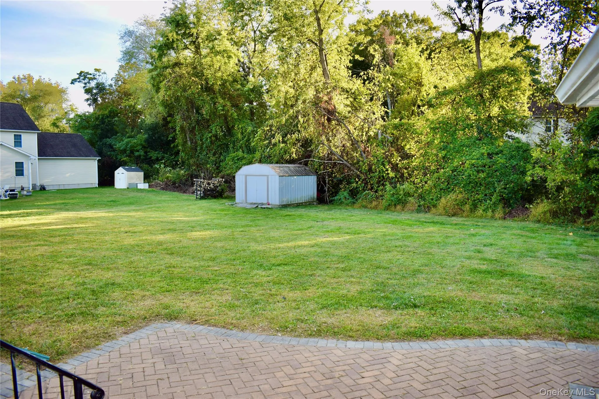 View of grassy yard with a storage unit and view of wooded area View of grassy yard with a storage unit and view of wooded area