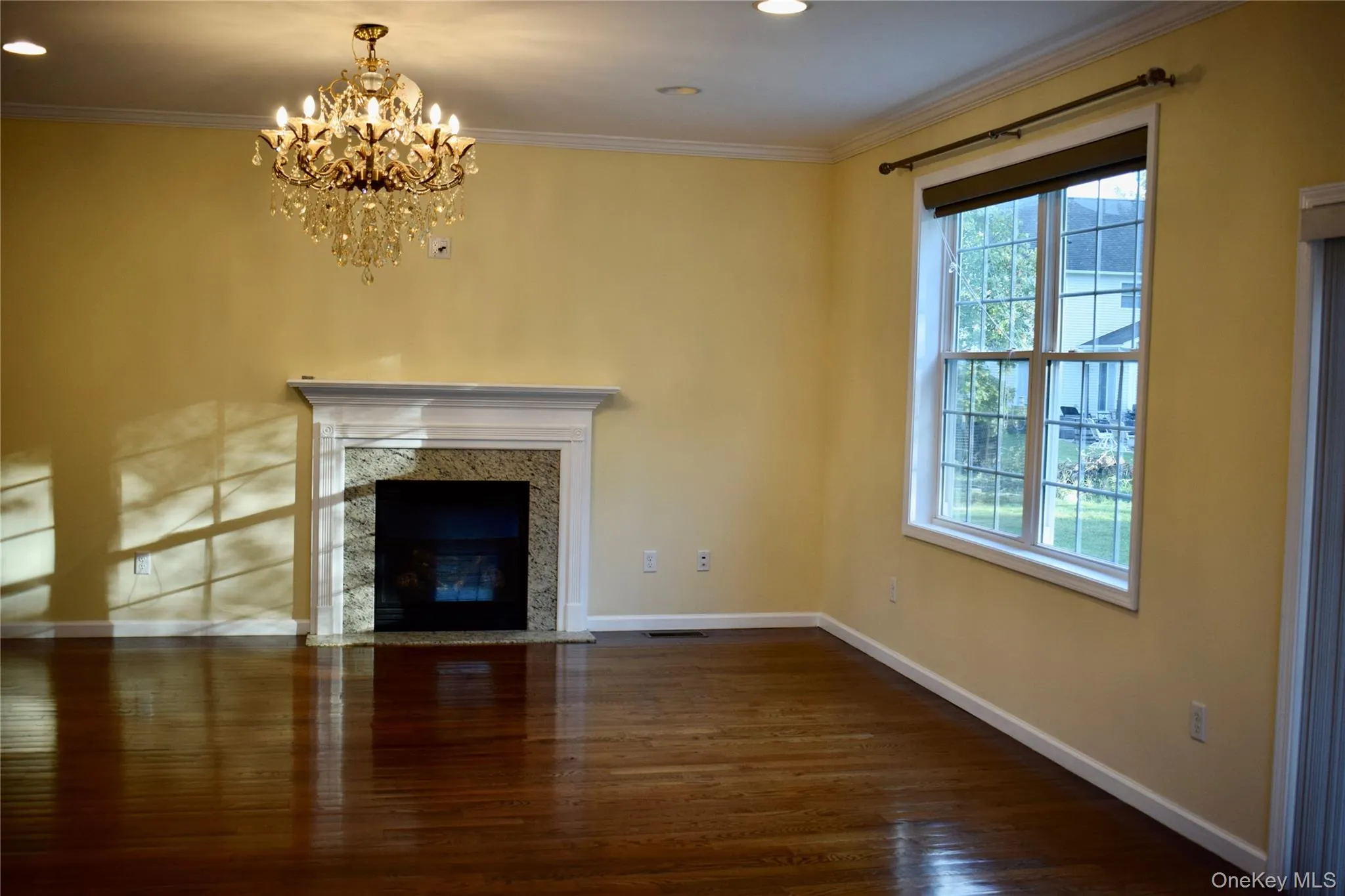 Unfurnished living room featuring dark wood-style flooring, crown molding, a fireplace, recessed lighting, and a chandelier Unfurnished living room featuring dark wood-style flooring, crown molding, a fireplace, recessed lighting, and a chandelier