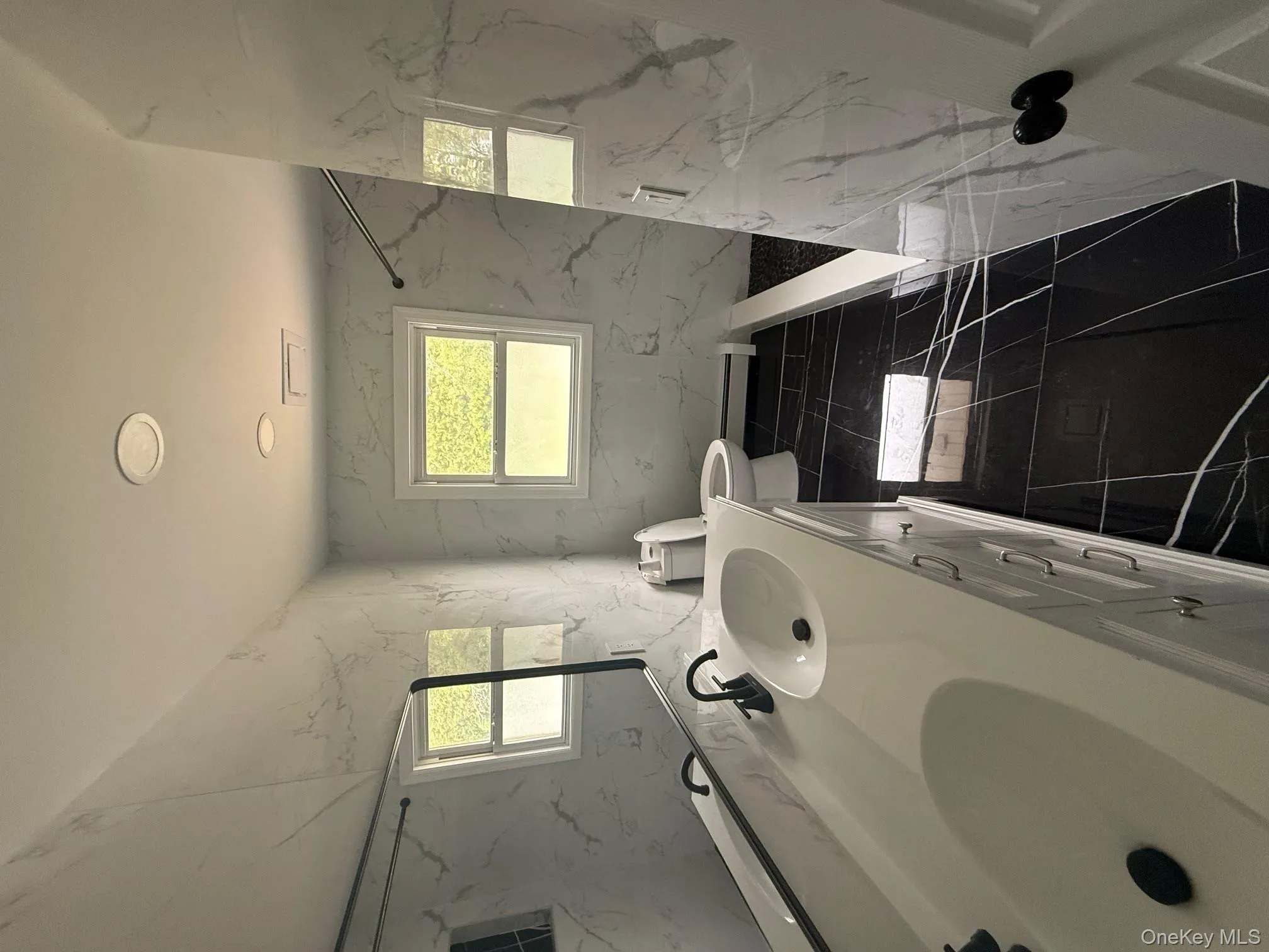 Full bathroom with double vanity, plenty of natural light, a marble finish shower, and a baseboard radiator Full bathroom with double vanity, plenty of natural light, a marble finish shower, and a baseboard radiator