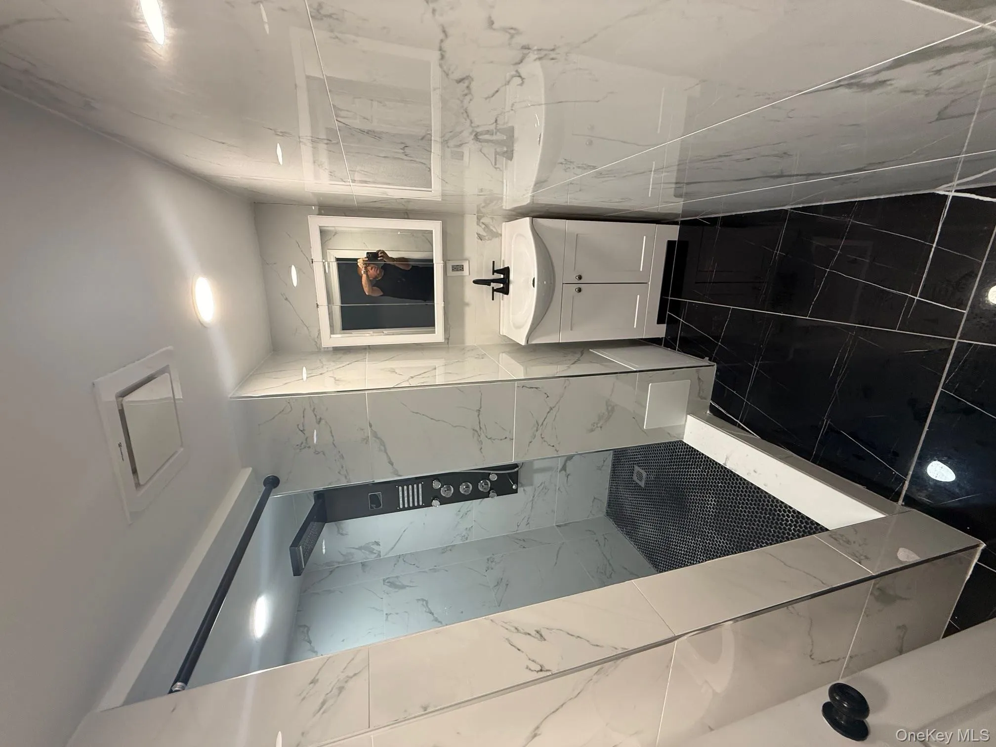 Full bath featuring vanity, a marble finish shower, tile walls, stone wall, and recessed lighting Full bath featuring vanity, a marble finish shower, tile walls, stone wall, and recessed lighting