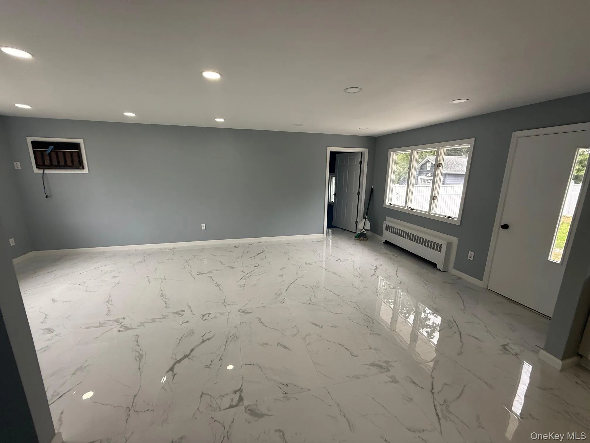 Empty room featuring recessed lighting, light marble finish flooring, and radiator Empty room featuring recessed lighting, light marble finish flooring, and radiator
