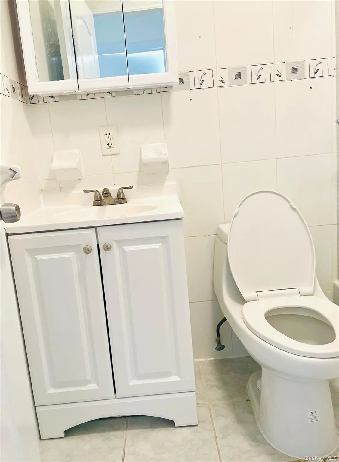 Bathroom with tile walls, vanity, light tile patterned floors, and decorative backsplash Bathroom with tile walls, vanity, light tile patterned floors, and decorative backsplash