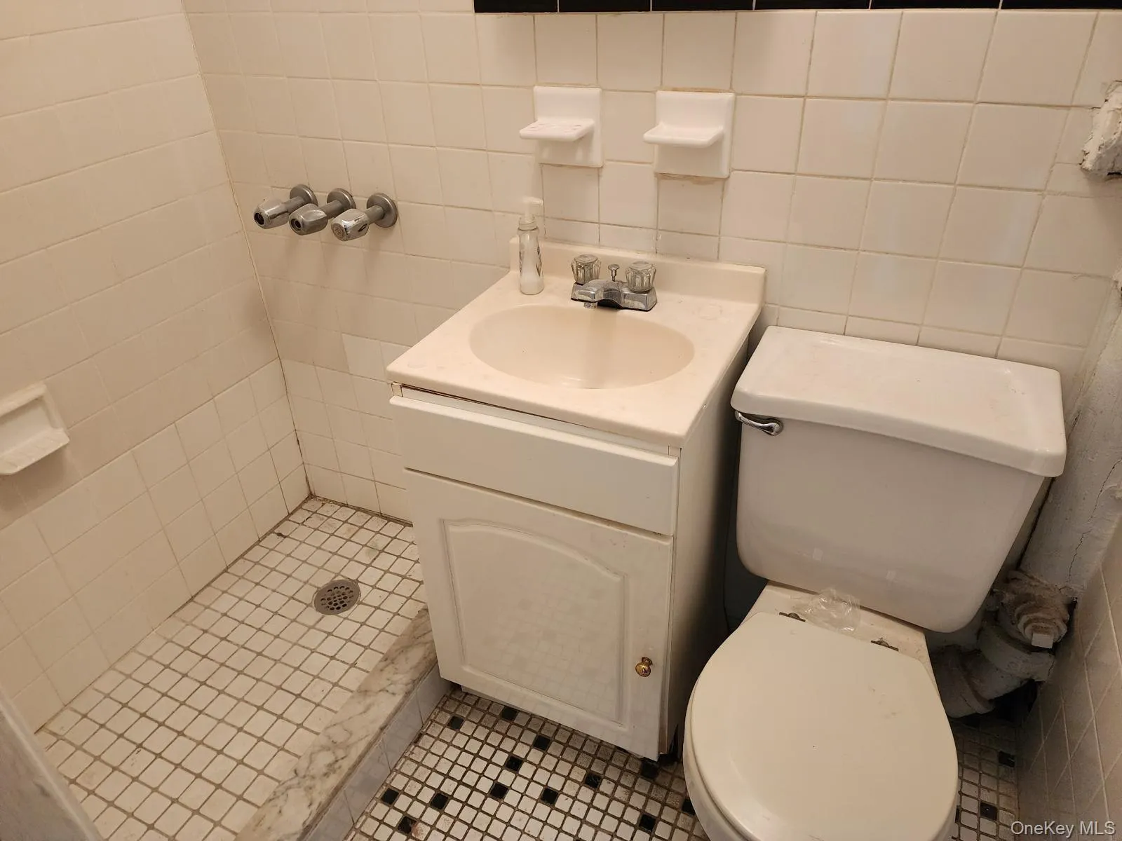 Bathroom featuring tile walls, vanity, a stall shower, and tile patterned floors Bathroom featuring tile walls, vanity, a stall shower, and tile patterned floors