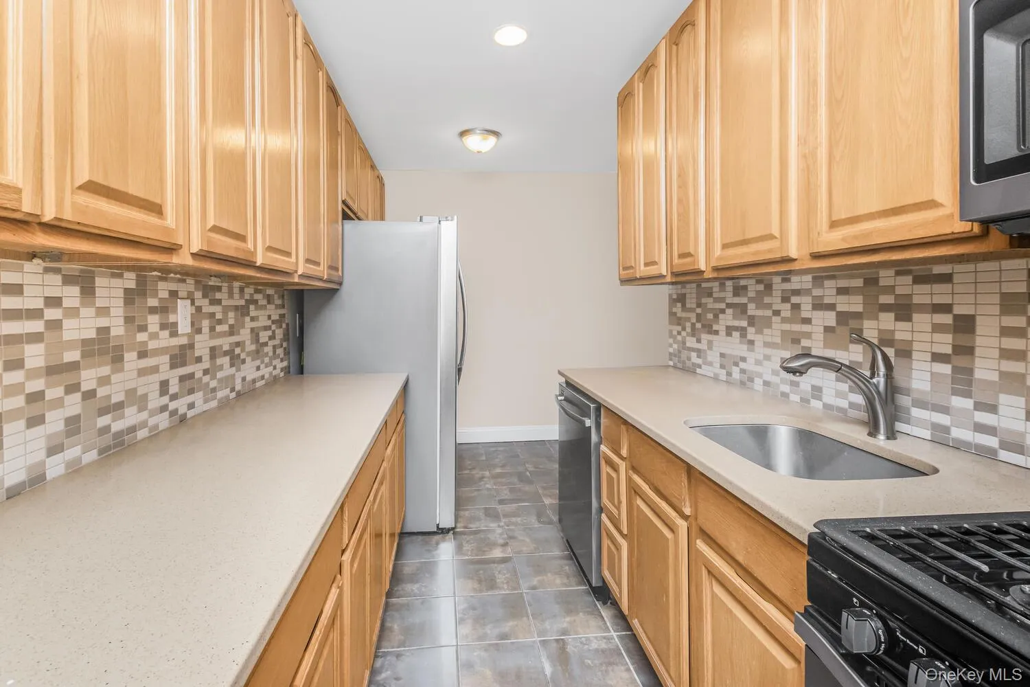 Kitchen with decorative backsplash, appliances with stainless steel finishes, light stone countertops, recessed lighting, and light brown cabinetry Kitchen with decorative backsplash, appliances with stainless steel finishes, light stone countertops, recessed lighting, and light brown cabinetry