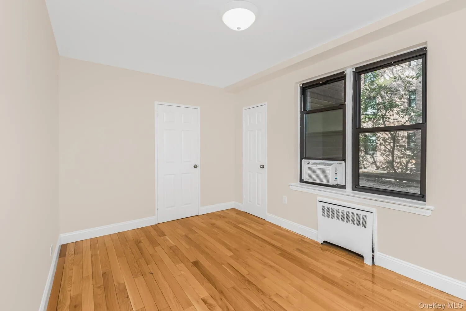 Unfurnished room with radiator, light wood finished floors, and cooling unit Unfurnished room with radiator, light wood finished floors, and cooling unit