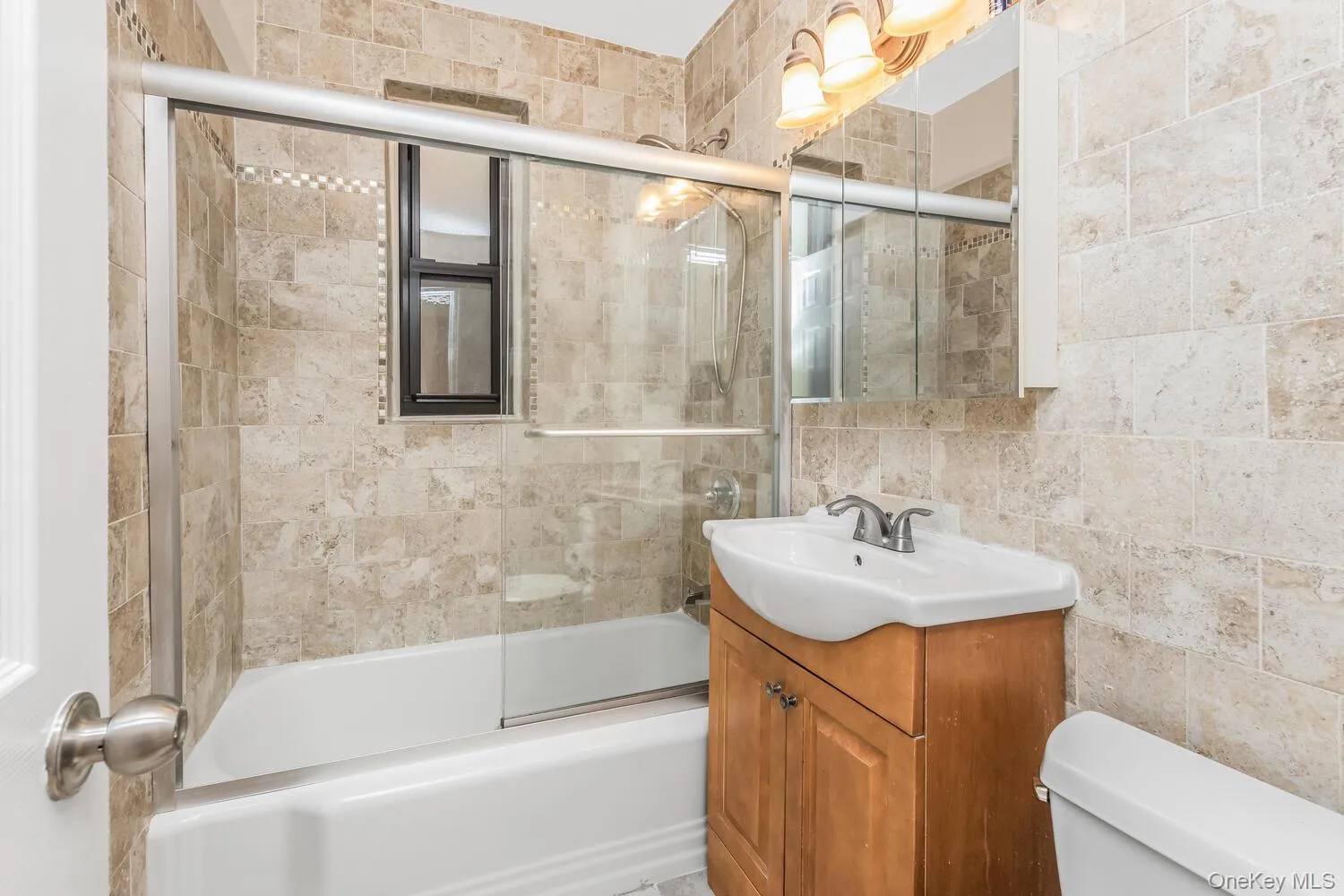Full bath with vanity, shower / bath combination with glass door, and tile walls Full bath with vanity, shower / bath combination with glass door, and tile walls