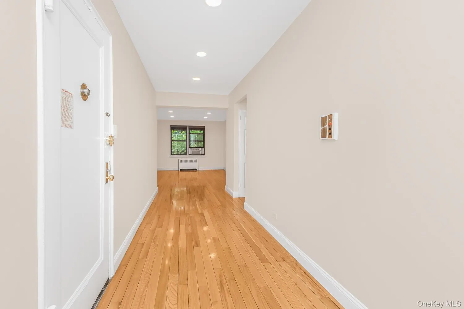 Hallway with recessed lighting, light wood-style floors, and radiator Hallway with recessed lighting, light wood-style floors, and radiator