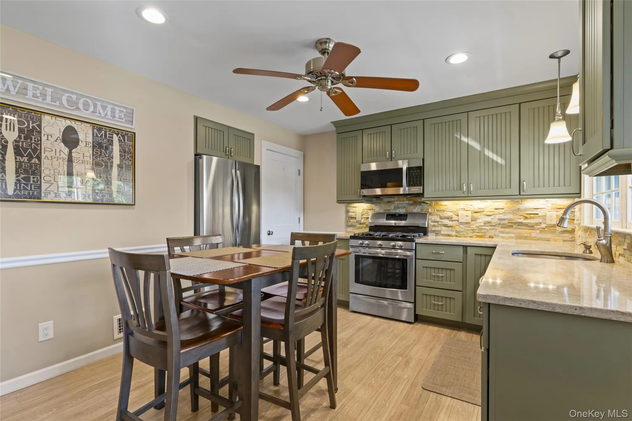 Kitchen featuring green cabinetry, light stone countertops, appliances with stainless steel finishes, tasteful backsplash, and fan Kitchen featuring green cabinetry, light stone countertops, appliances with stainless steel finishes, tasteful backsplash, and fan