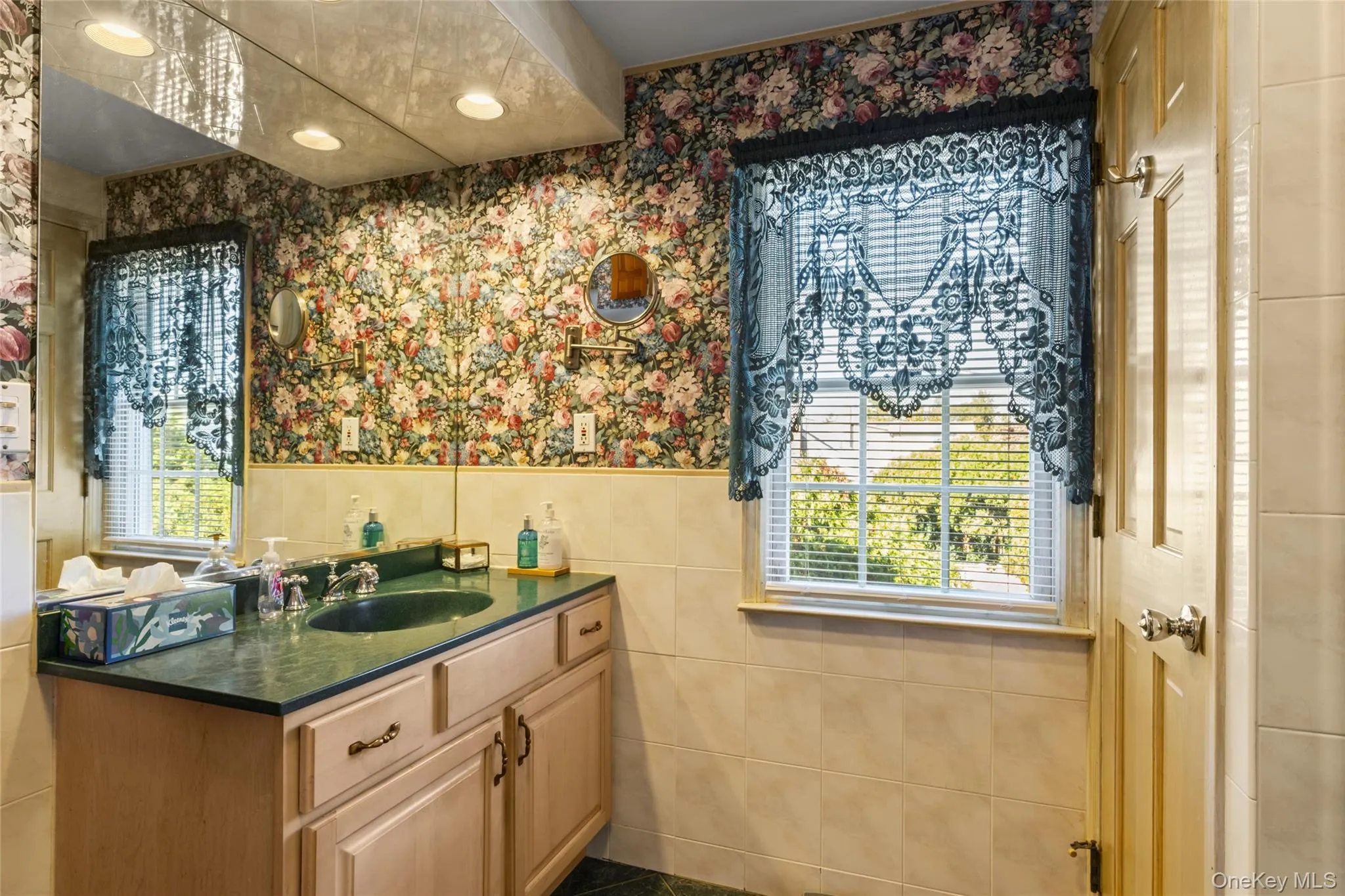 Bathroom with wallpapered walls, vanity, tile walls, a wainscoted wall, and recessed lighting Bathroom with wallpapered walls, vanity, tile walls, a wainscoted wall, and recessed lighting