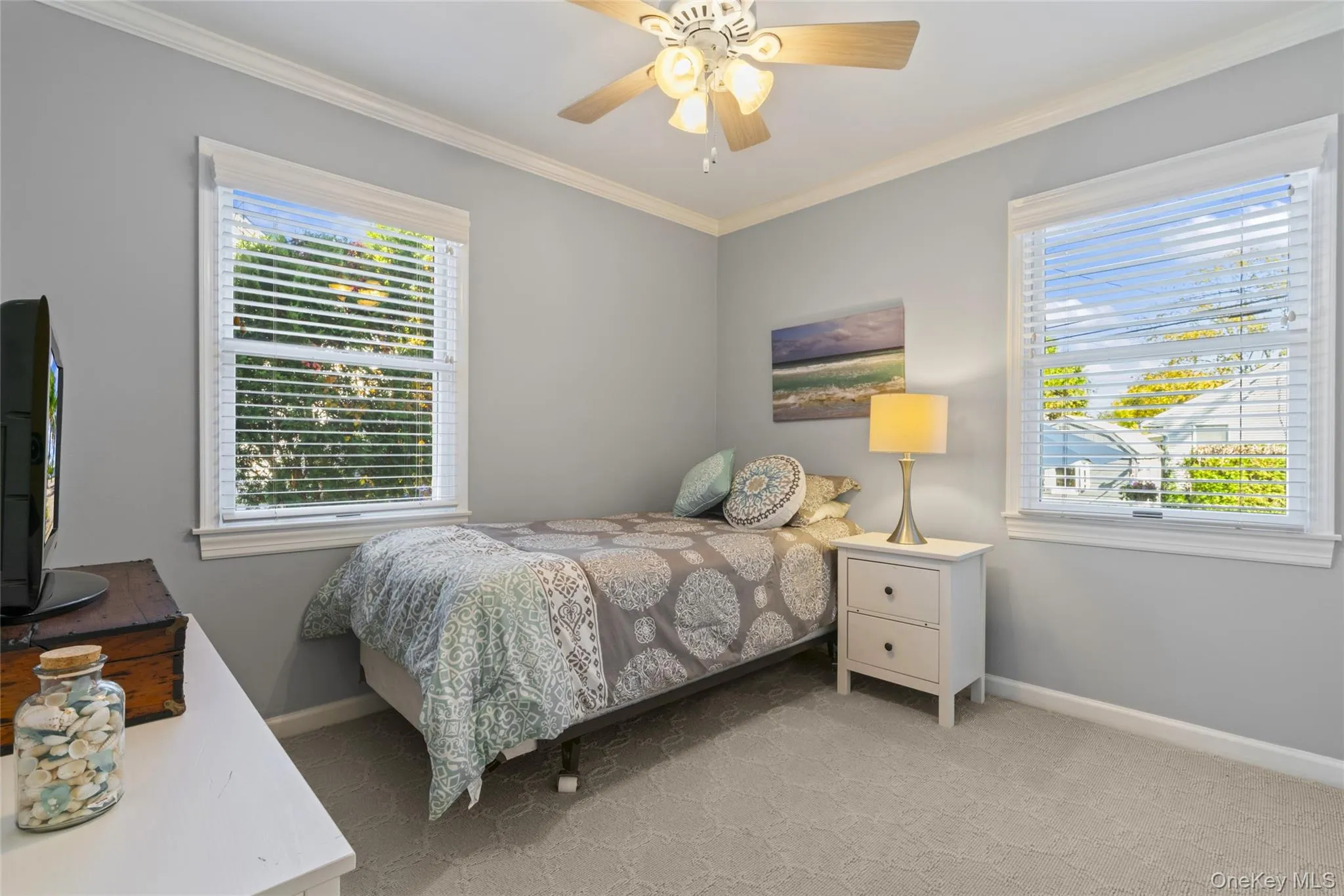 Bedroom featuring ornamental molding, ceiling fan, multiple windows, and light carpet Bedroom featuring ornamental molding, ceiling fan, multiple windows, and light carpet