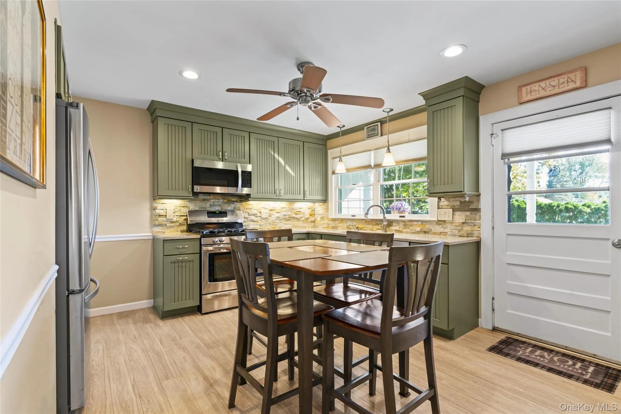 Kitchen featuring green cabinets, appliances with stainless steel finishes, light wood-style floors, backsplash, and recessed lighting Kitchen featuring green cabinets, appliances with stainless steel finishes, light wood-style floors, backsplash, and recessed lighting