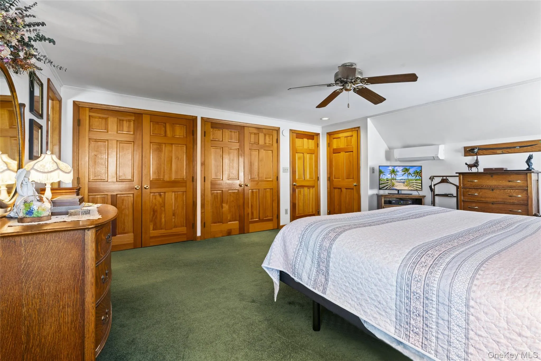 Bedroom with two closets, ceiling fan, a wall mounted air conditioner, and third small closet Bedroom with two closets, ceiling fan, a wall mounted air conditioner, and third small closet