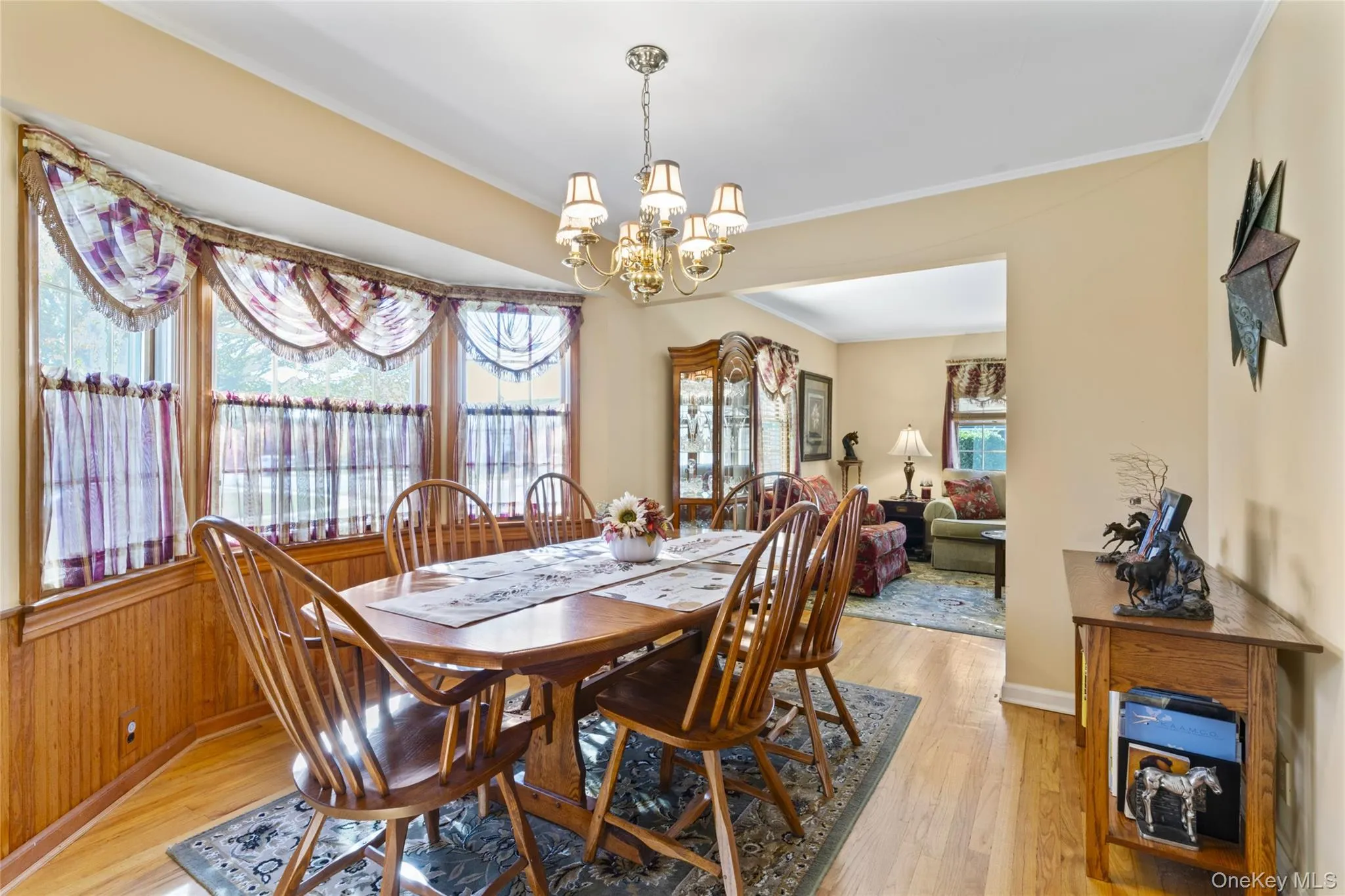 Dining space featuring ornamental molding, light wood-style flooring, and a chandelier Dining space featuring ornamental molding, light wood-style flooring, and a chandelier