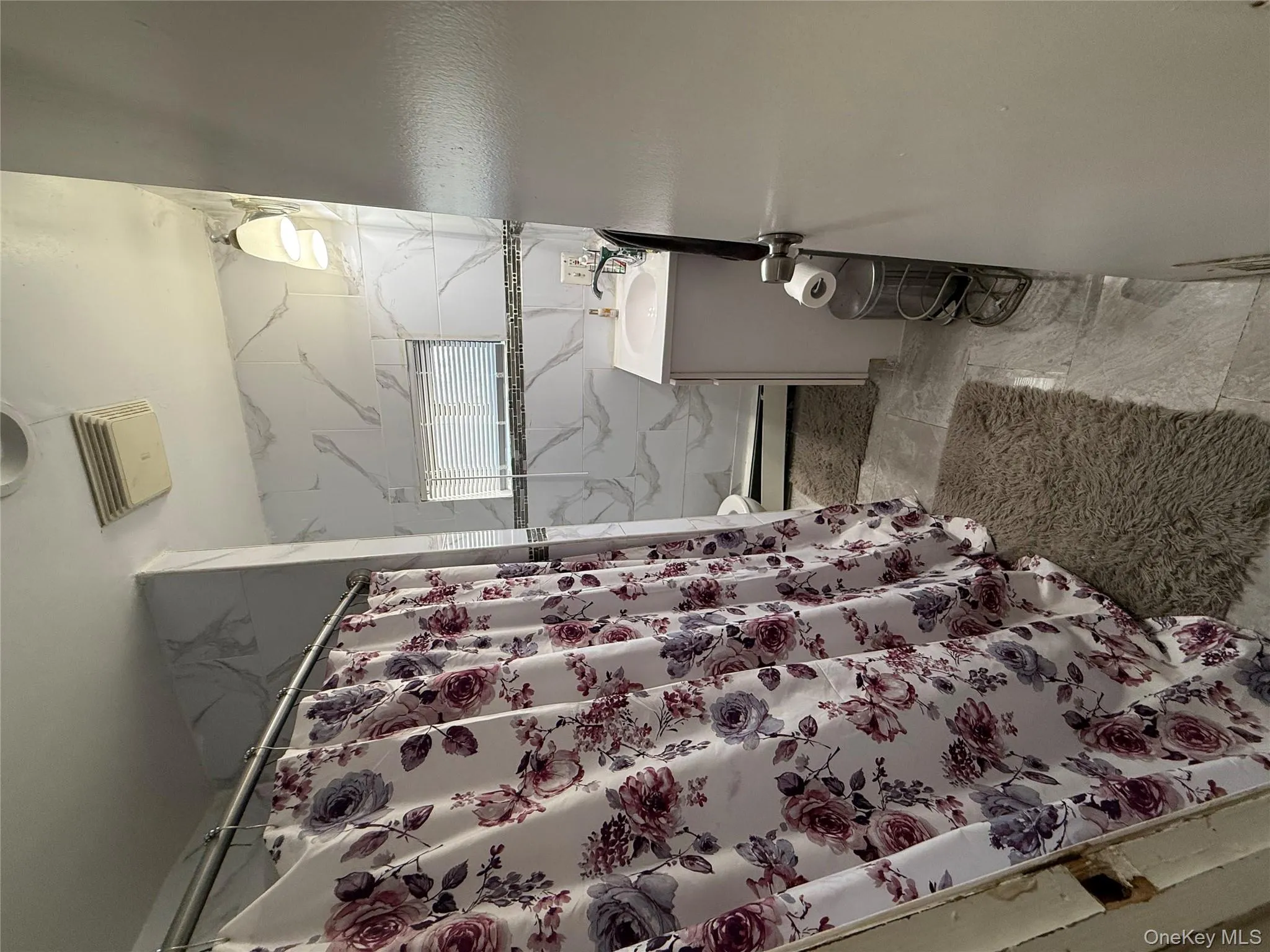 Bathroom featuring vanity, a shower with curtain, baseboard heating, and tile walls Bathroom featuring vanity, a shower with curtain, baseboard heating, and tile walls