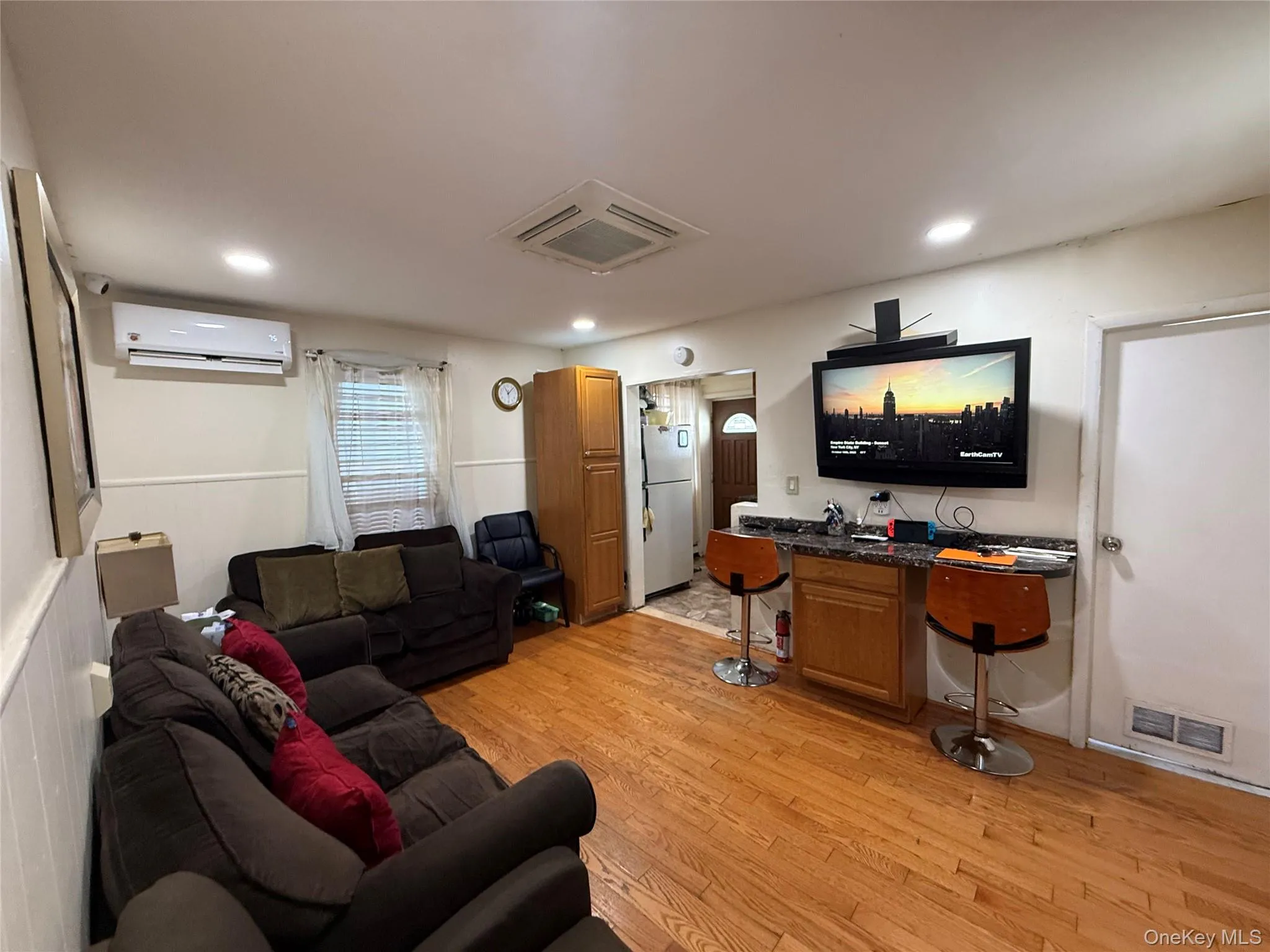 Living room featuring light wood-style floors, cooling unit, recessed lighting, and a wall unit AC Living room featuring light wood-style floors, cooling unit, recessed lighting, and a wall unit AC