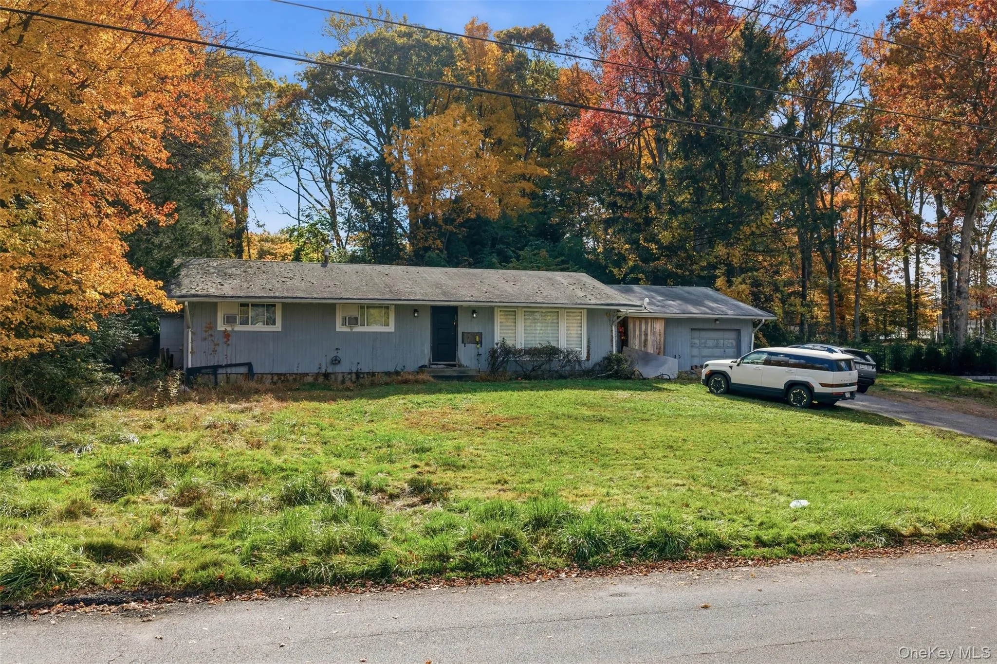 Ranch-style home featuring an attached garage, a front lawn, and asphalt driveway Ranch-style home featuring an attached garage, a front lawn, and asphalt driveway