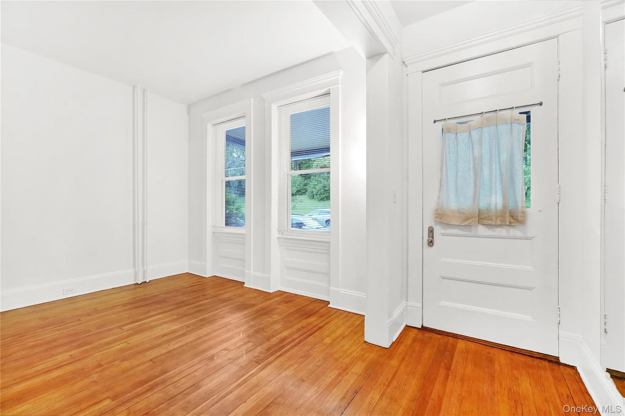Doorway to outside with wood finished floors and baseboards Doorway to outside with wood finished floors and baseboards