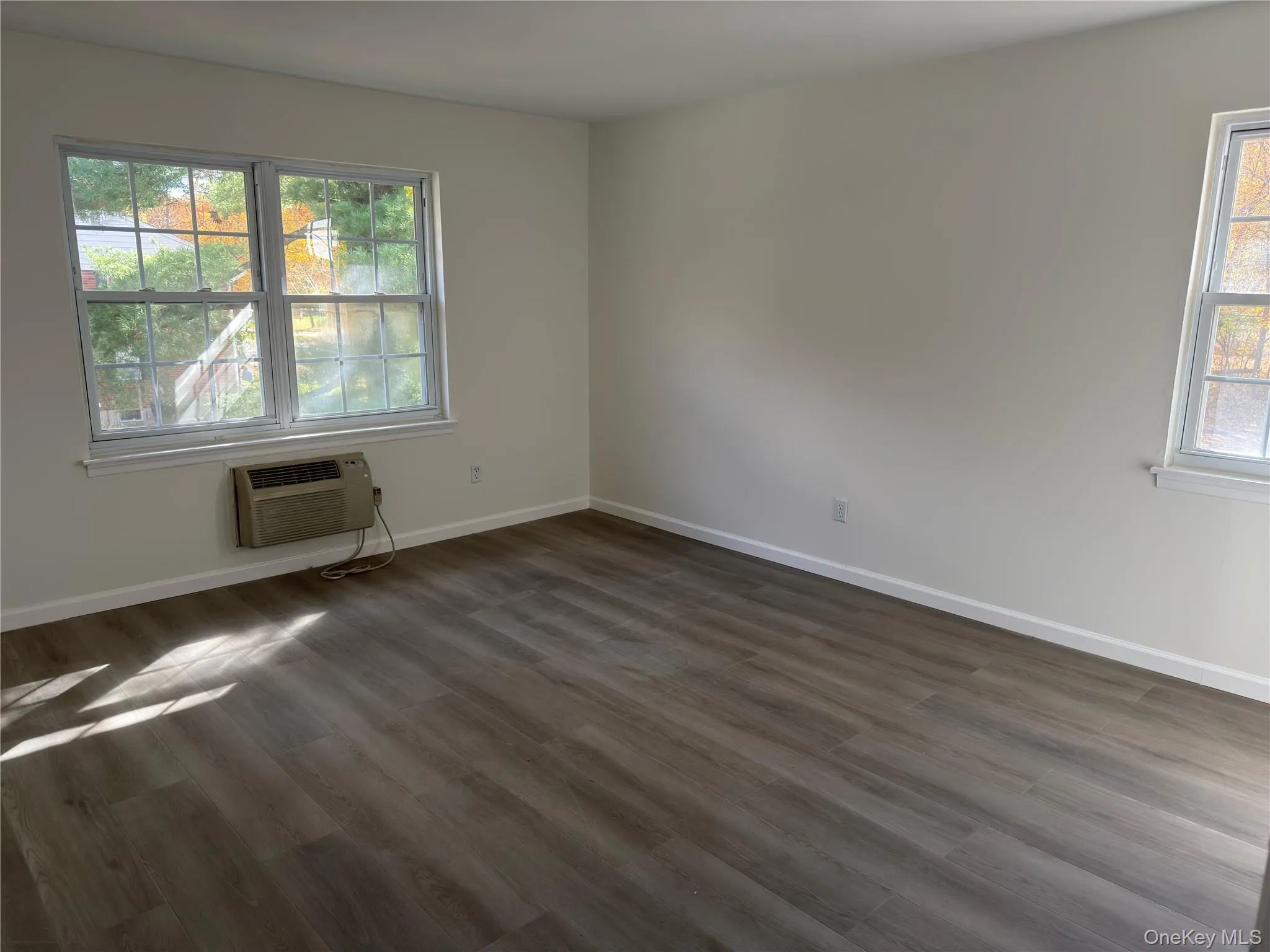 Unfurnished room with dark wood-type flooring and baseboards Unfurnished room with dark wood-type flooring and baseboards