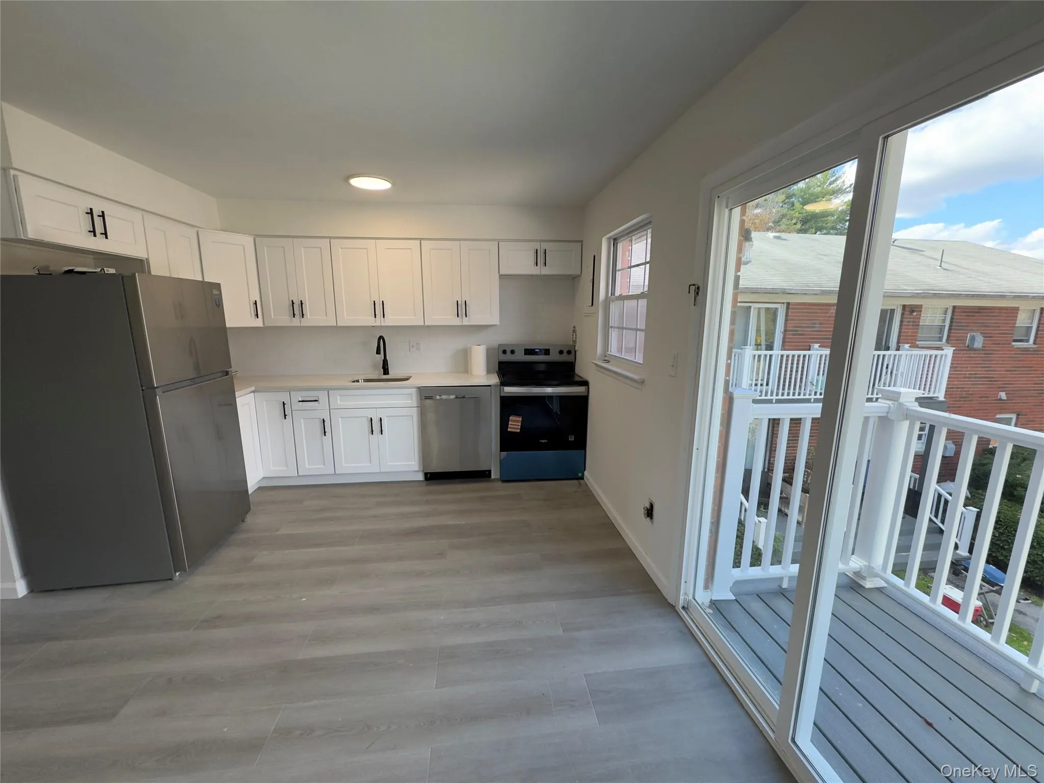 Kitchen featuring appliances with stainless steel finishes, light countertops, white cabinets, and light wood-style flooring Kitchen featuring appliances with stainless steel finishes, light countertops, white cabinets, and light wood-style flooring
