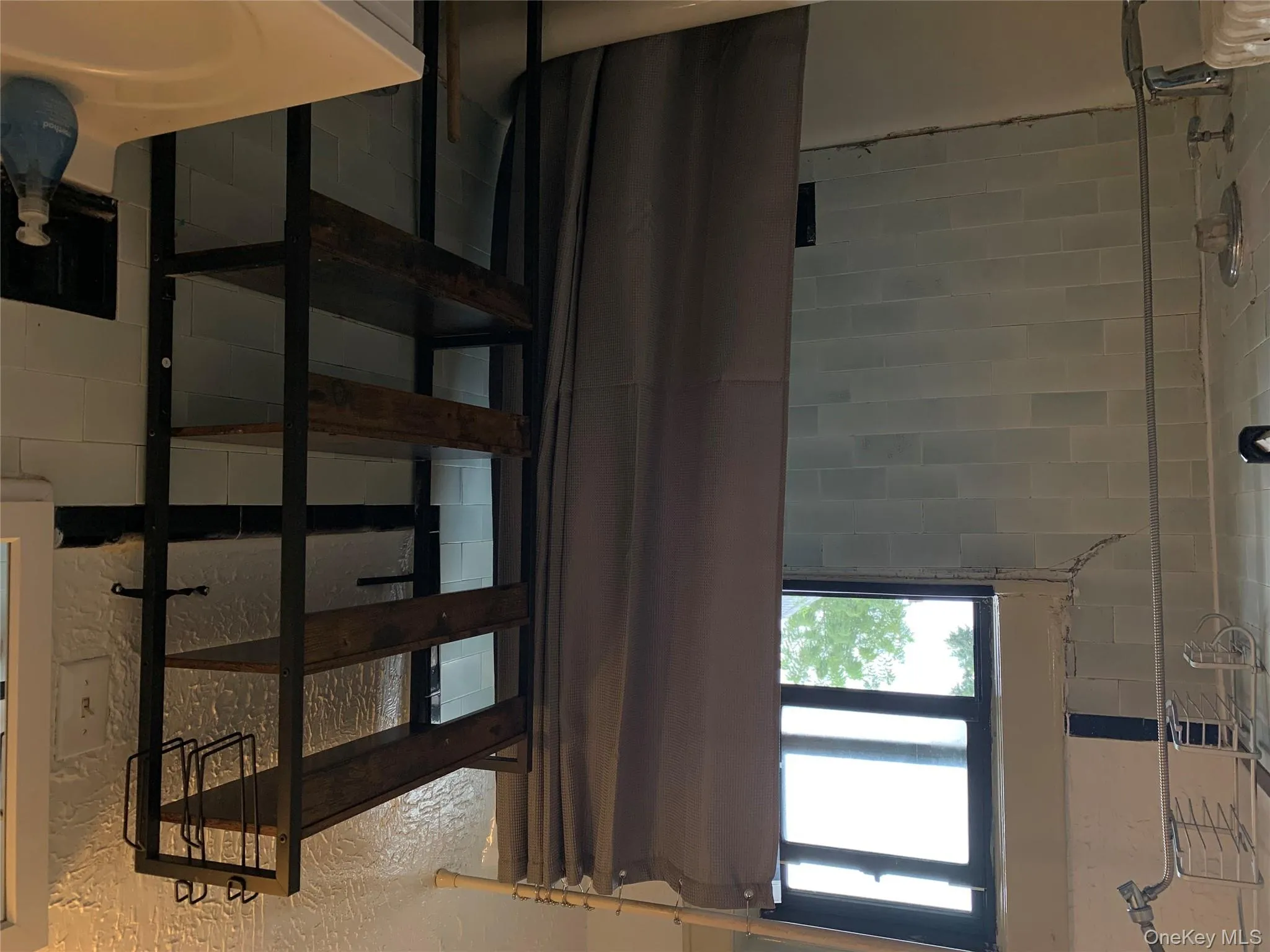 Full bathroom featuring shower / bath combo with shower curtain, vanity, and a textured wall Full bathroom featuring shower / bath combo with shower curtain, vanity, and a textured wall