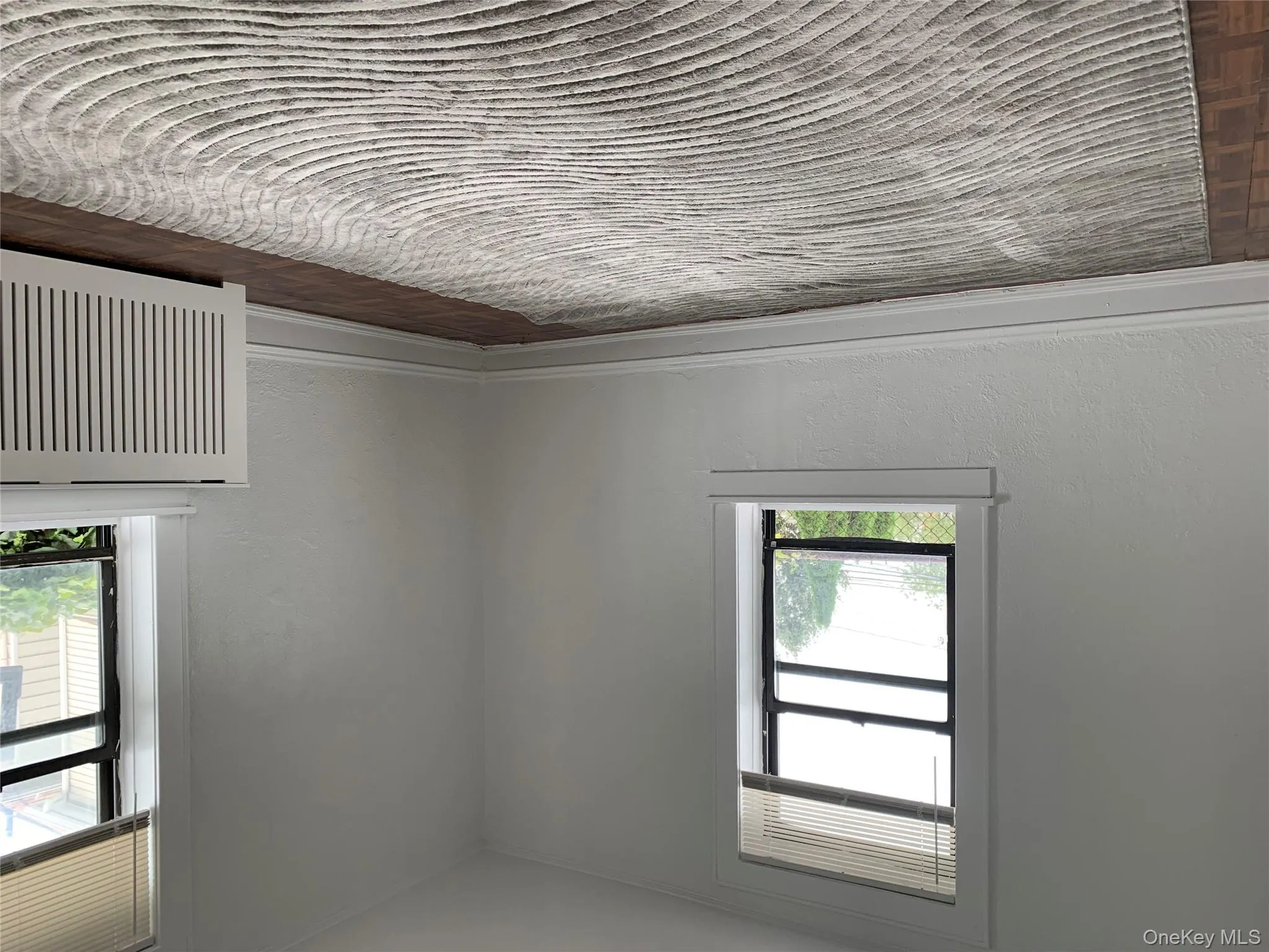 Unfurnished room with radiator, a textured wall, and parquet flooring Unfurnished room with radiator, a textured wall, and parquet flooring