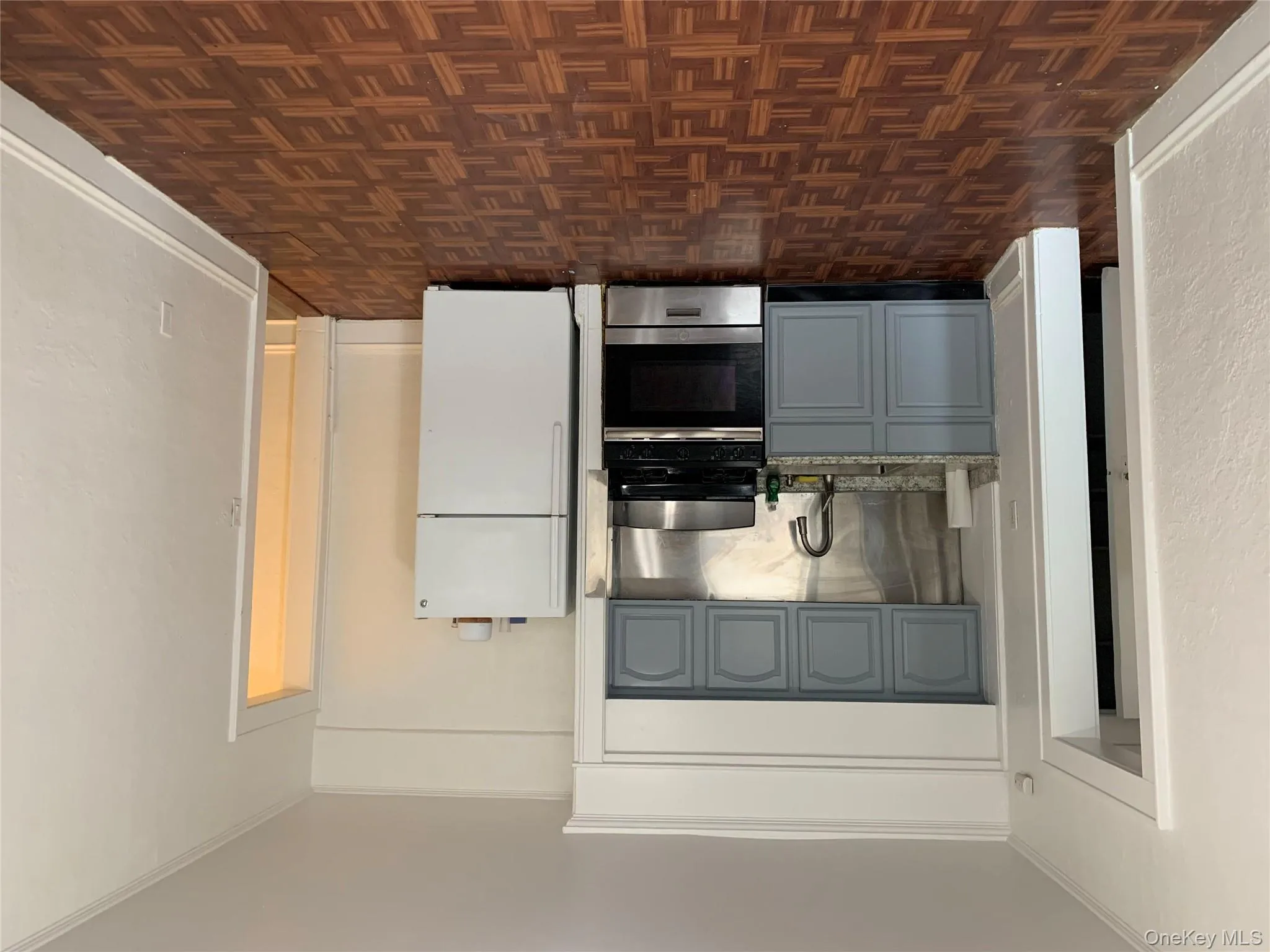 Kitchen with range, stainless steel fridge, gray cabinets, ornamental molding, and light stone counters Kitchen with range, stainless steel fridge, gray cabinets, ornamental molding, and light stone counters