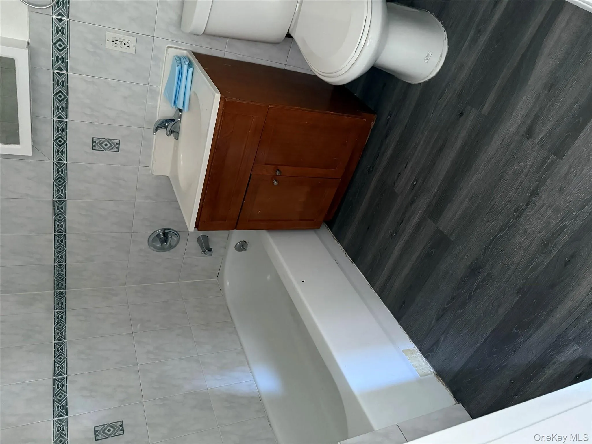 Full bathroom with tile walls, dark wood-type flooring, vanity, and a tub Full bathroom with tile walls, dark wood-type flooring, vanity, and a tub