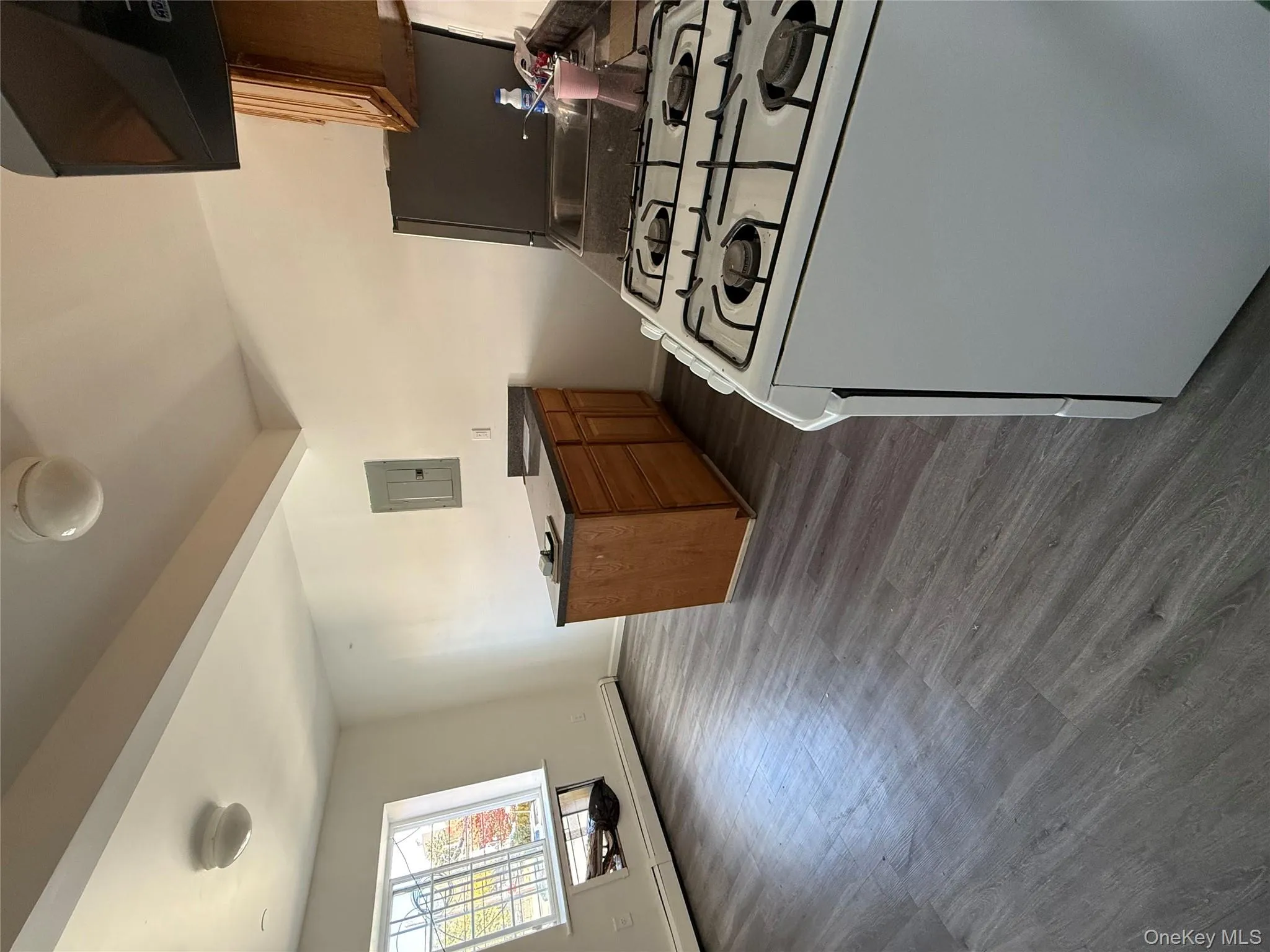 Kitchen featuring stove, brown cabinetry, baseboard heating, a peninsula, and dark wood finished floors Kitchen featuring stove, brown cabinetry, baseboard heating, a peninsula, and dark wood finished floors