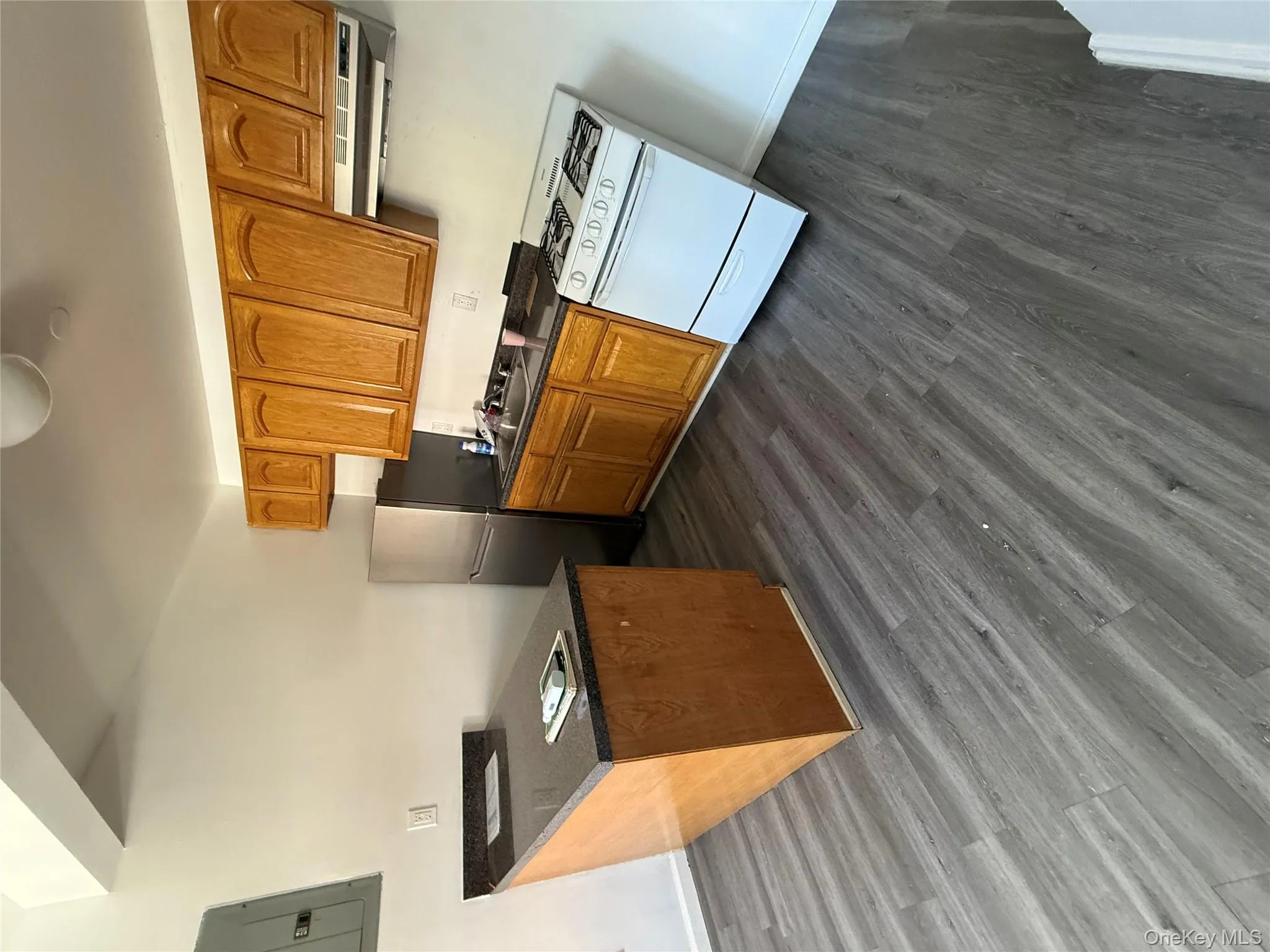 Kitchen featuring range, a peninsula, white refrigerator, dark wood-type flooring, and brown cabinetry Kitchen featuring range, a peninsula, white refrigerator, dark wood-type flooring, and brown cabinetry
