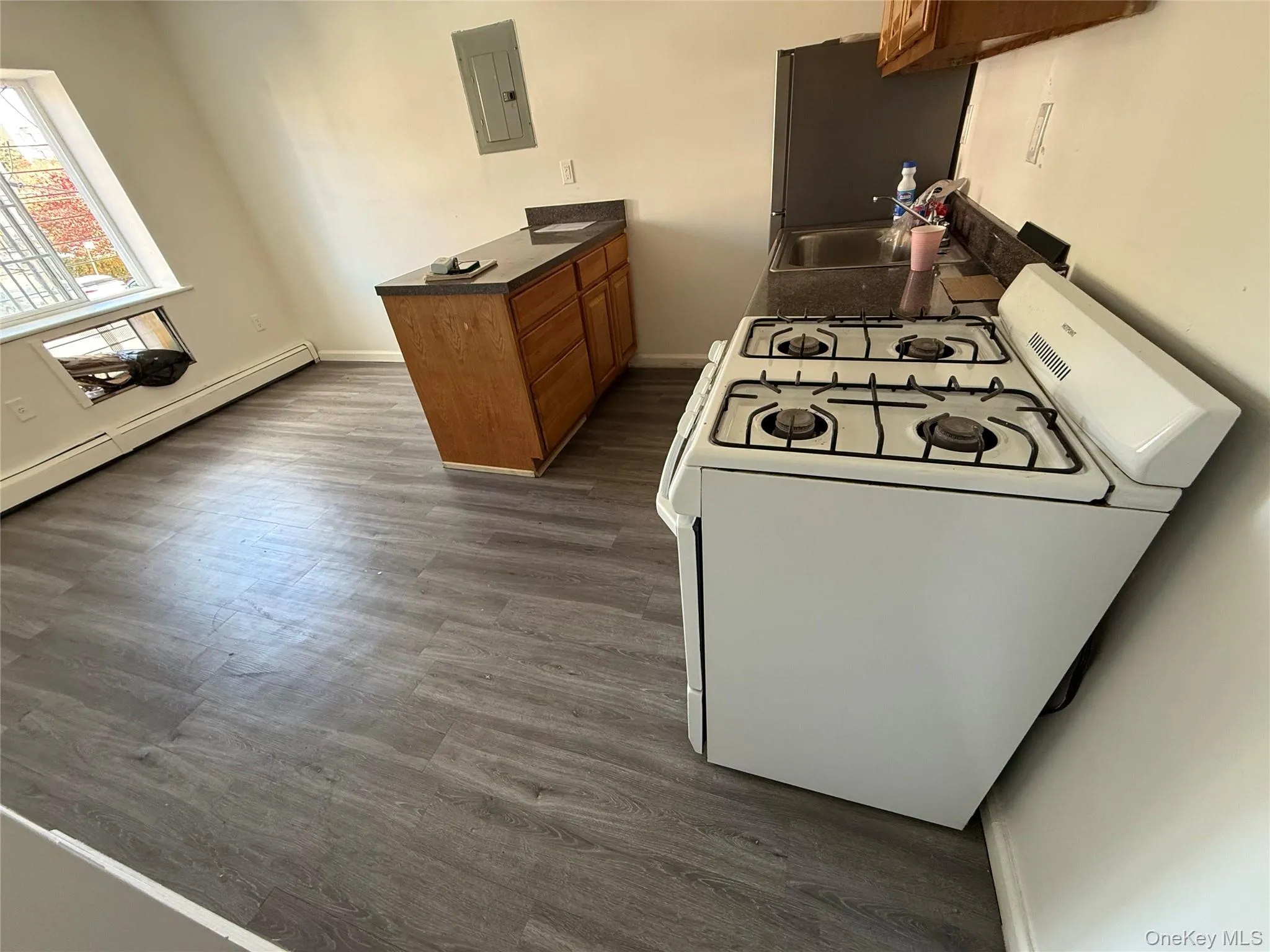 Kitchen featuring white gas stove, brown cabinets, dark countertops, and dark wood-type flooring Kitchen featuring white gas stove, brown cabinets, dark countertops, and dark wood-type flooring