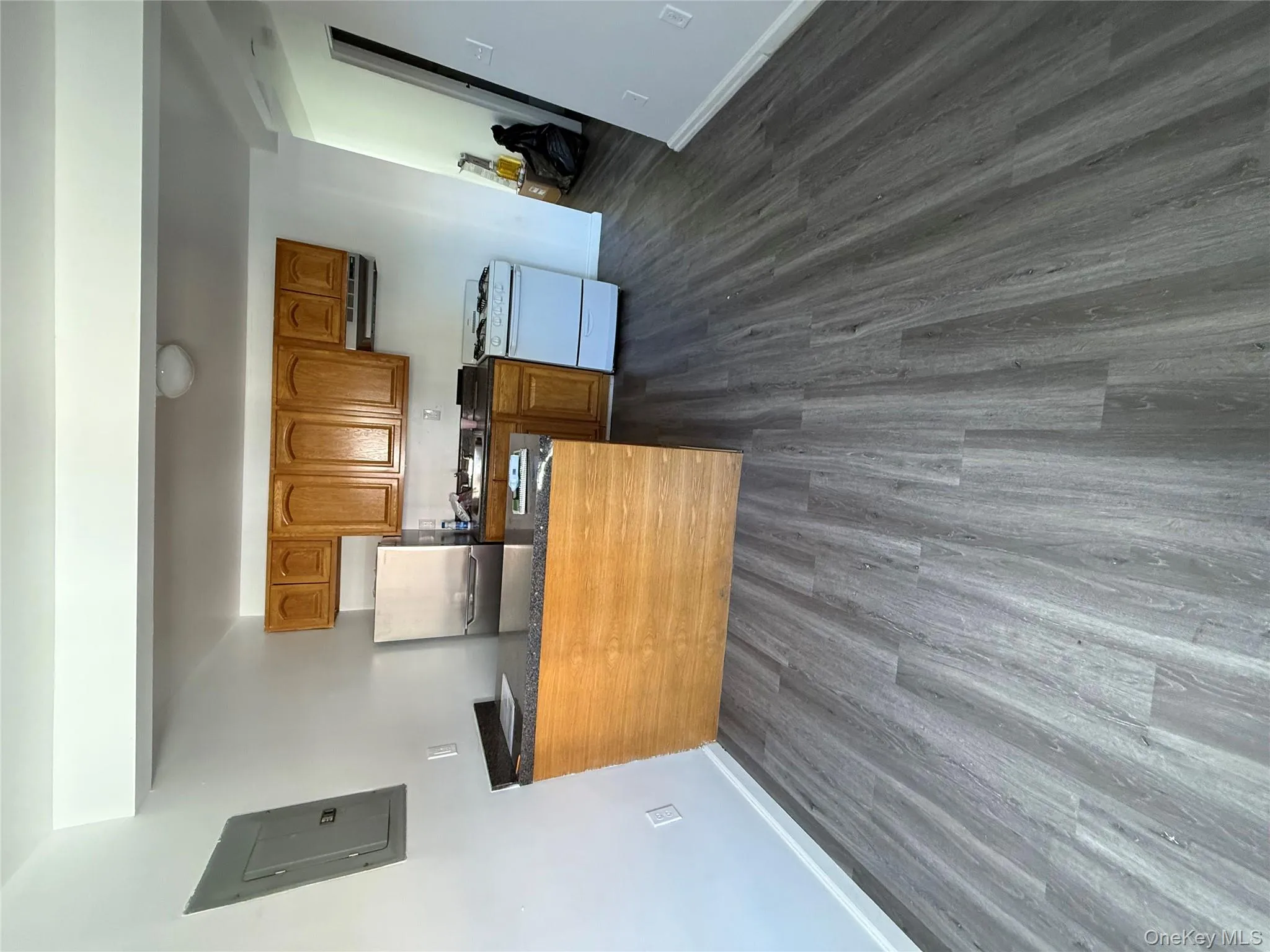 Kitchen with brown cabinetry, a peninsula, white fridge, and dark wood-style floors Kitchen with brown cabinetry, a peninsula, white fridge, and dark wood-style floors