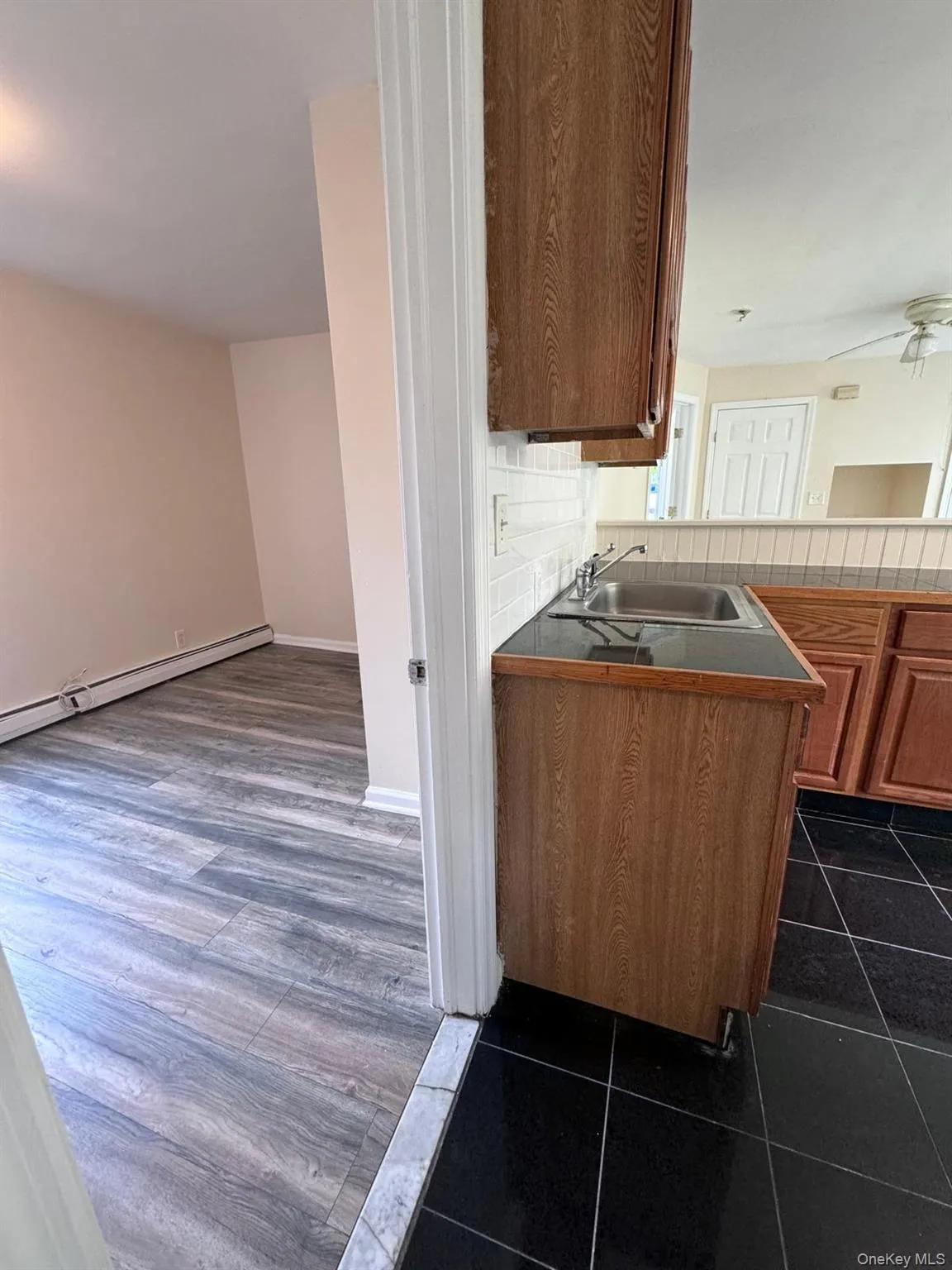 Kitchen with a baseboard heating unit, brown cabinets, decorative backsplash, and dark tile patterned floors Kitchen with a baseboard heating unit, brown cabinets, decorative backsplash, and dark tile patterned floors