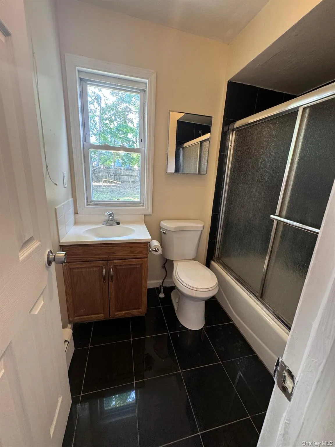 Full bathroom featuring tile patterned flooring, vanity, and enclosed tub / shower combo Full bathroom featuring tile patterned flooring, vanity, and enclosed tub / shower combo