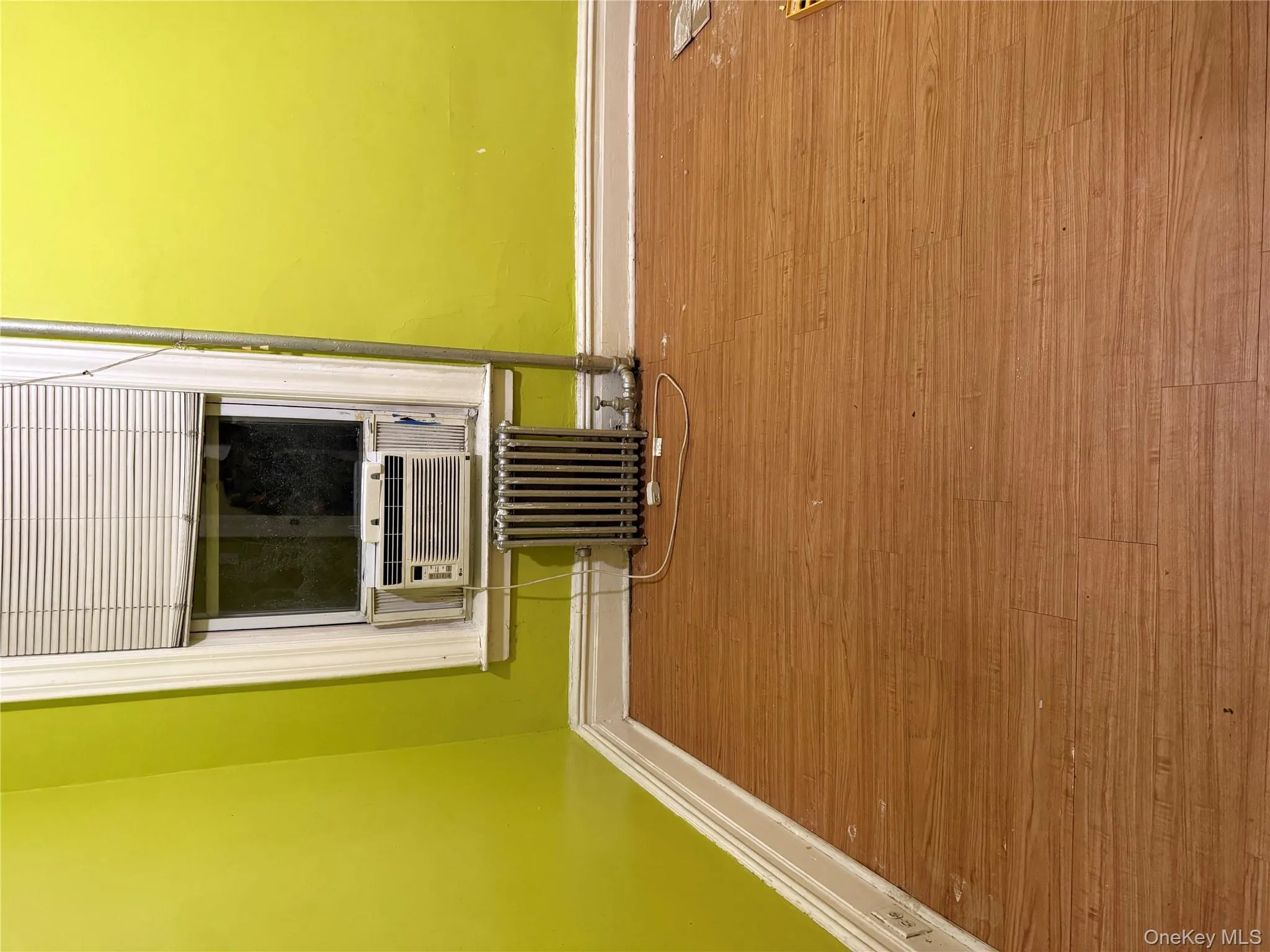 Unfurnished room with radiator and wood finished floors Unfurnished room with radiator and wood finished floors