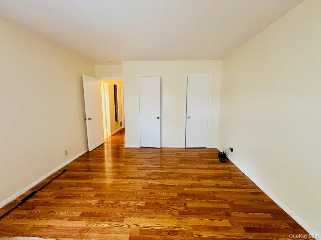 Unfurnished bedroom with light wood-style flooring and two closets Unfurnished bedroom with light wood-style flooring and two closets