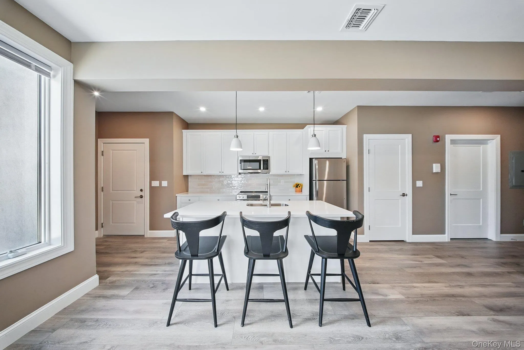Kitchen featuring plenty of natural light, white cabinetry, backsplash, and recessed lighting Kitchen featuring plenty of natural light, white cabinetry, backsplash, and recessed lighting