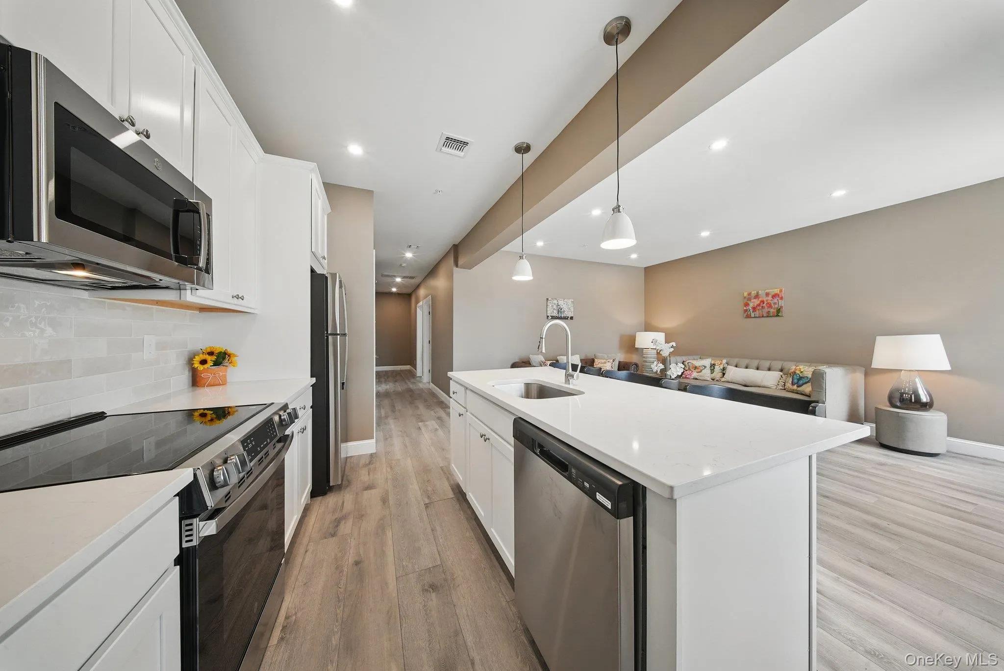 Kitchen with appliances with stainless steel finishes, open floor plan, white cabinets, pendant lighting, and recessed lighting Kitchen with appliances with stainless steel finishes, open floor plan, white cabinets, pendant lighting, and recessed lighting
