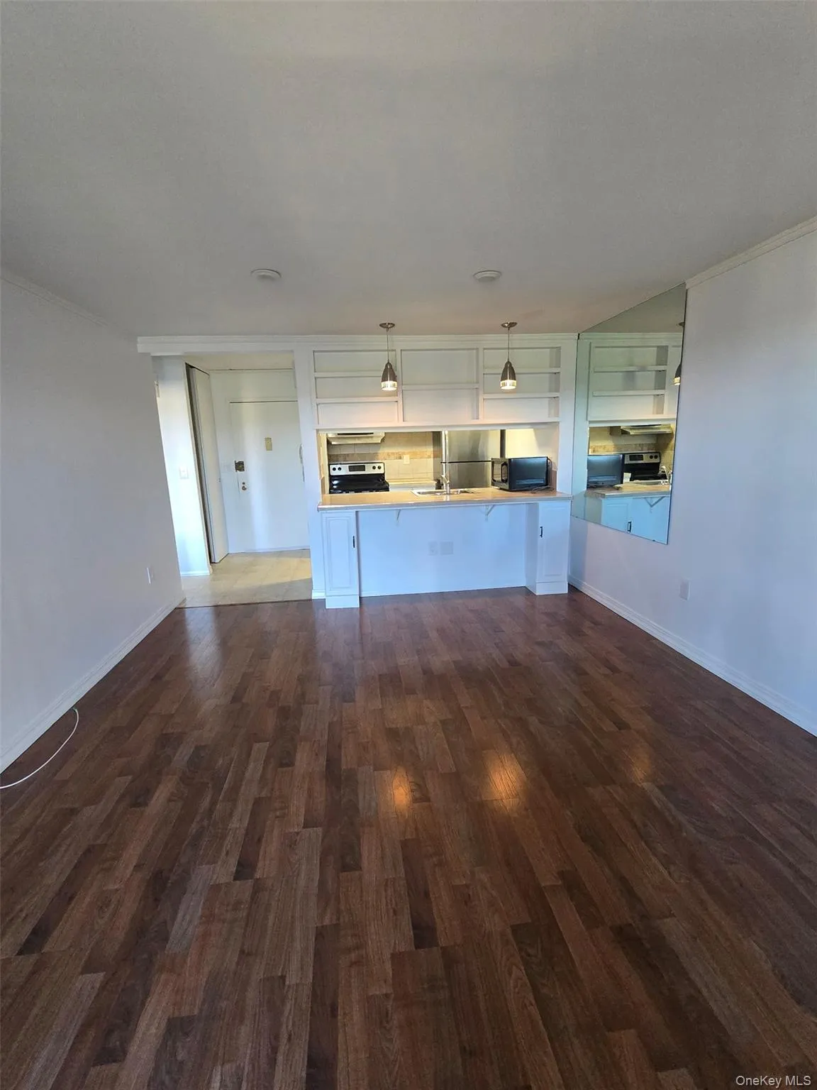 Unfurnished living room with ornamental molding and dark wood-style floors Unfurnished living room with ornamental molding and dark wood-style floors