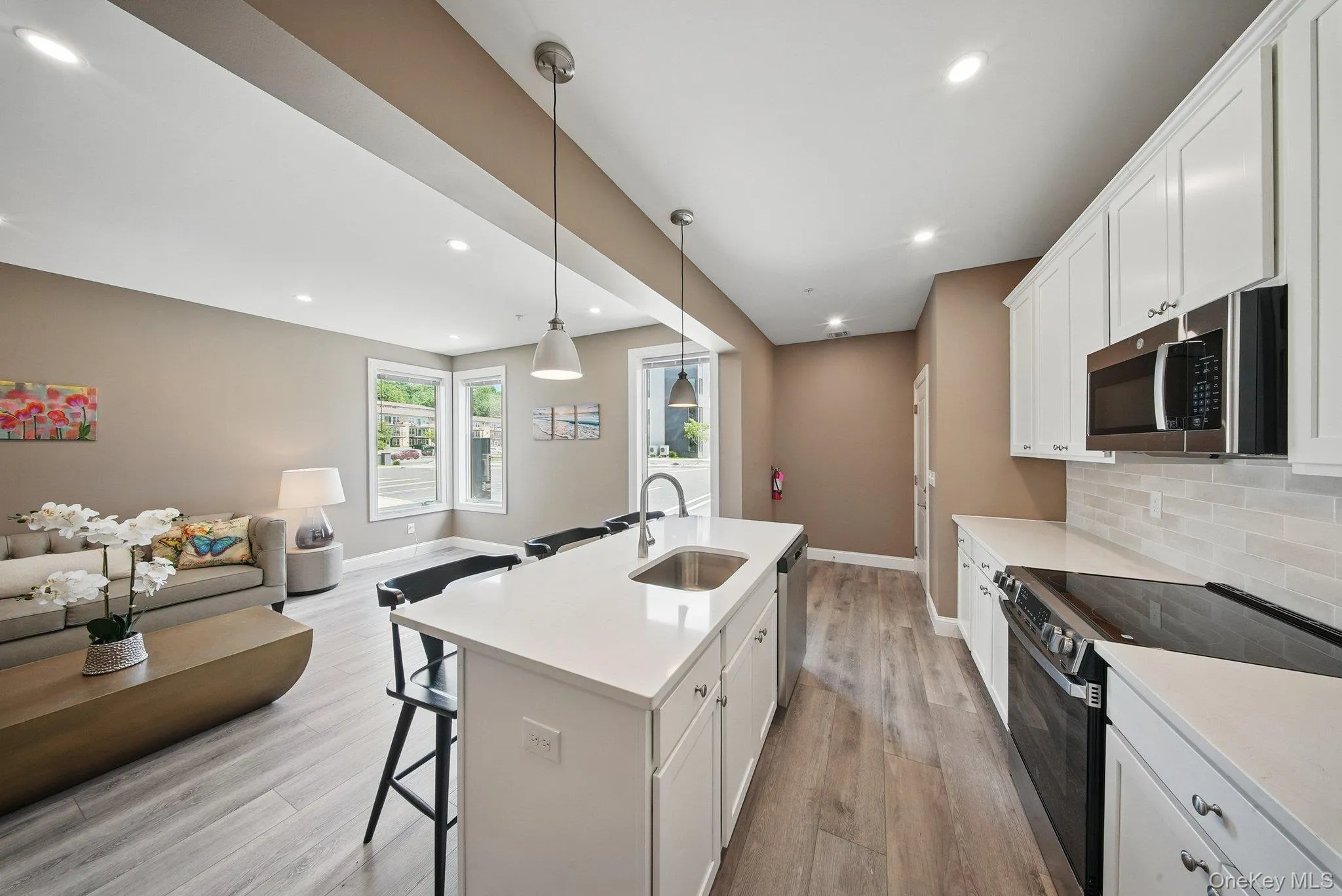 Kitchen featuring stainless steel appliances, open floor plan, a breakfast bar, pendant lighting, and white cabinetry Kitchen featuring stainless steel appliances, open floor plan, a breakfast bar, pendant lighting, and white cabinetry