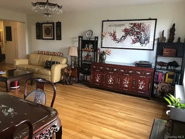 Living room featuring light wood finished floors and a chandelier Living room featuring light wood finished floors and a chandelier