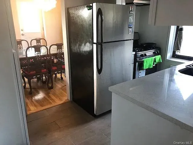 Kitchen featuring freestanding refrigerator, light countertops, white gas stove, and white cabinets Kitchen featuring freestanding refrigerator, light countertops, white gas stove, and white cabinets