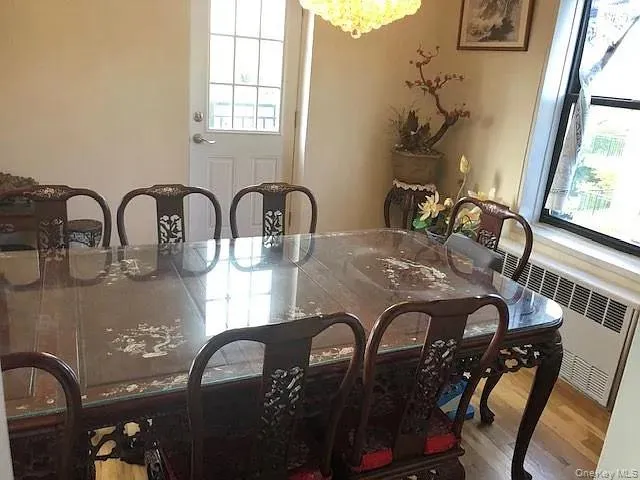 Dining room with radiator heating unit, wood finished floors, and a chandelier Dining room with radiator heating unit, wood finished floors, and a chandelier