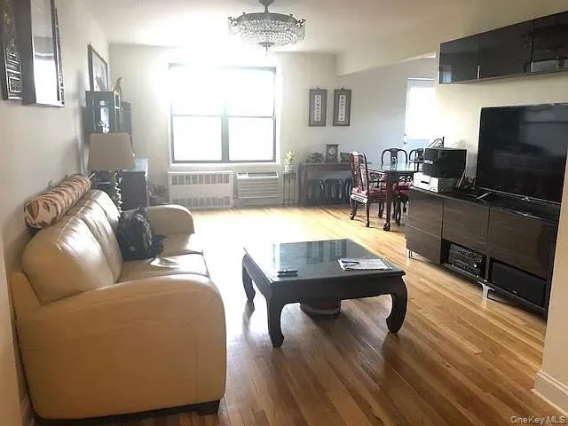 Living area with light wood finished floors and radiator heating unit Living area with light wood finished floors and radiator heating unit