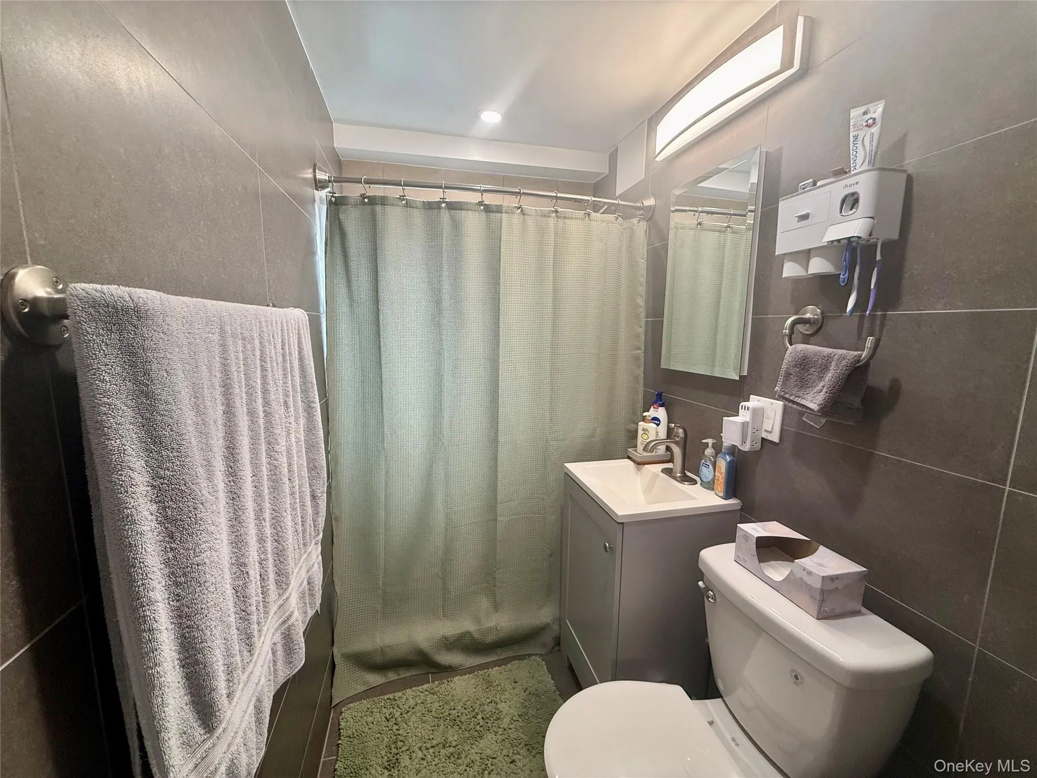 Full bathroom featuring tile walls, vanity, and a shower with shower curtain Full bathroom featuring tile walls, vanity, and a shower with shower curtain